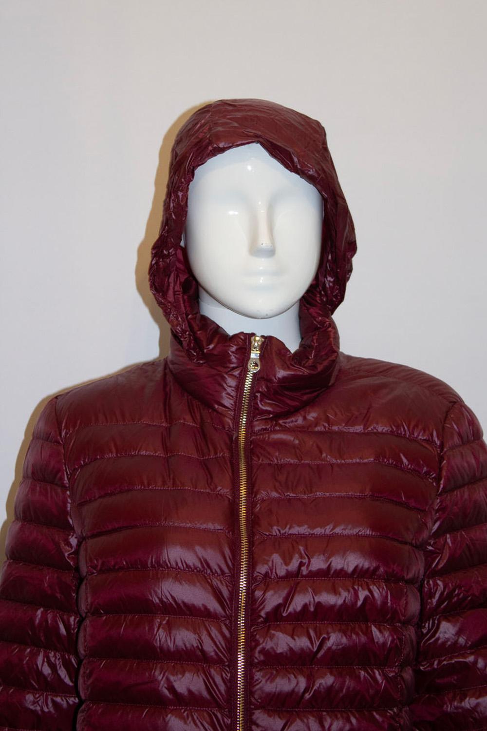 A chic and easy to wear ( and pack ) puffa jacket by 
Kate Spade . In a great burgundy colour, the jacket has two external and two internal pockets. The hood is zipped into the collar. The stuffing is 90% down and 10 % waterfowl feathers. Size