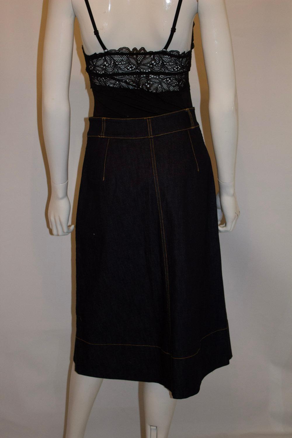 A great skirt for Summer or Fall by Kate Spade. 
In a dark denim with embroidery on the front , the skirt is A line with a button front opening. It has belt hoops and is unlined. Size US 4