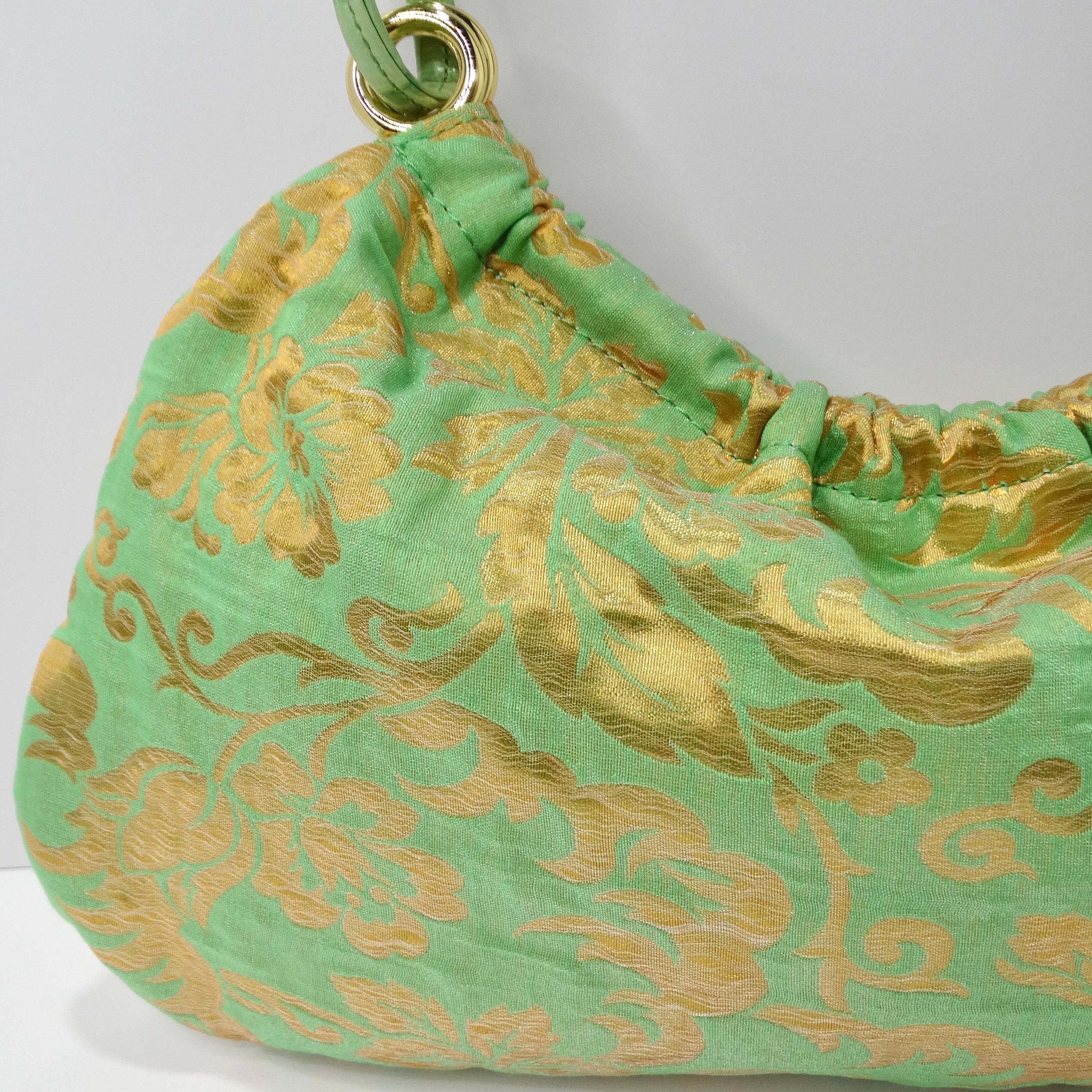 Introducing the Kate Spade Green Floral Shoulder Bag, a vibrant and playful accessory that adds a touch of fun to any ensemble. This bright green shoulder bag features metallic gold floral detailing, adding a whimsical and eye-catching element to