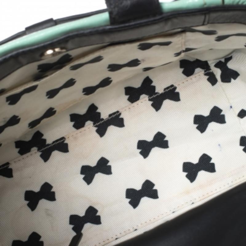 This easy-to-carry Kate Spade tote can be carried from office to brunches. The bag is made from mint green patent leather as well as black leather and it is elegantly held by two top handles and a shoulder strap. It is complete with a bow at the