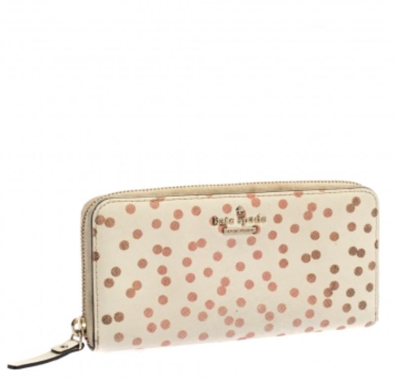 Fabriqué en cuir de haute qualité, ce portefeuille Kate Spade est à la fois simple et élégant. Il est orné de pois sur fond blanc et doté d'une fermeture à glissière qui permet d'accéder à plusieurs fentes et compartiments pour cartes.