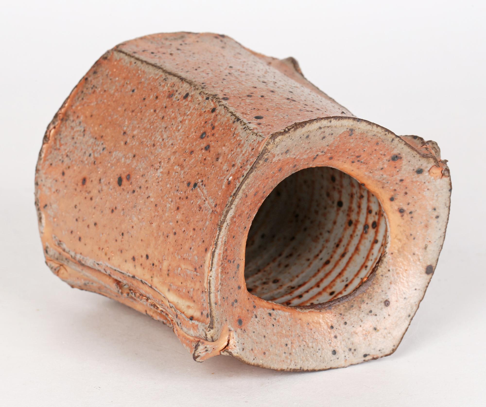 Eine handgefertigte, gedrungene, leicht spitz zulaufende, rhombische Vase aus Studiotöpferware in mattrosa Glasur von Katerina Evangelidou (Griechin, um 1960). Die viereckige Vase hat zwei ausbrechende vertikale Nähte an zwei Ecken mit einer