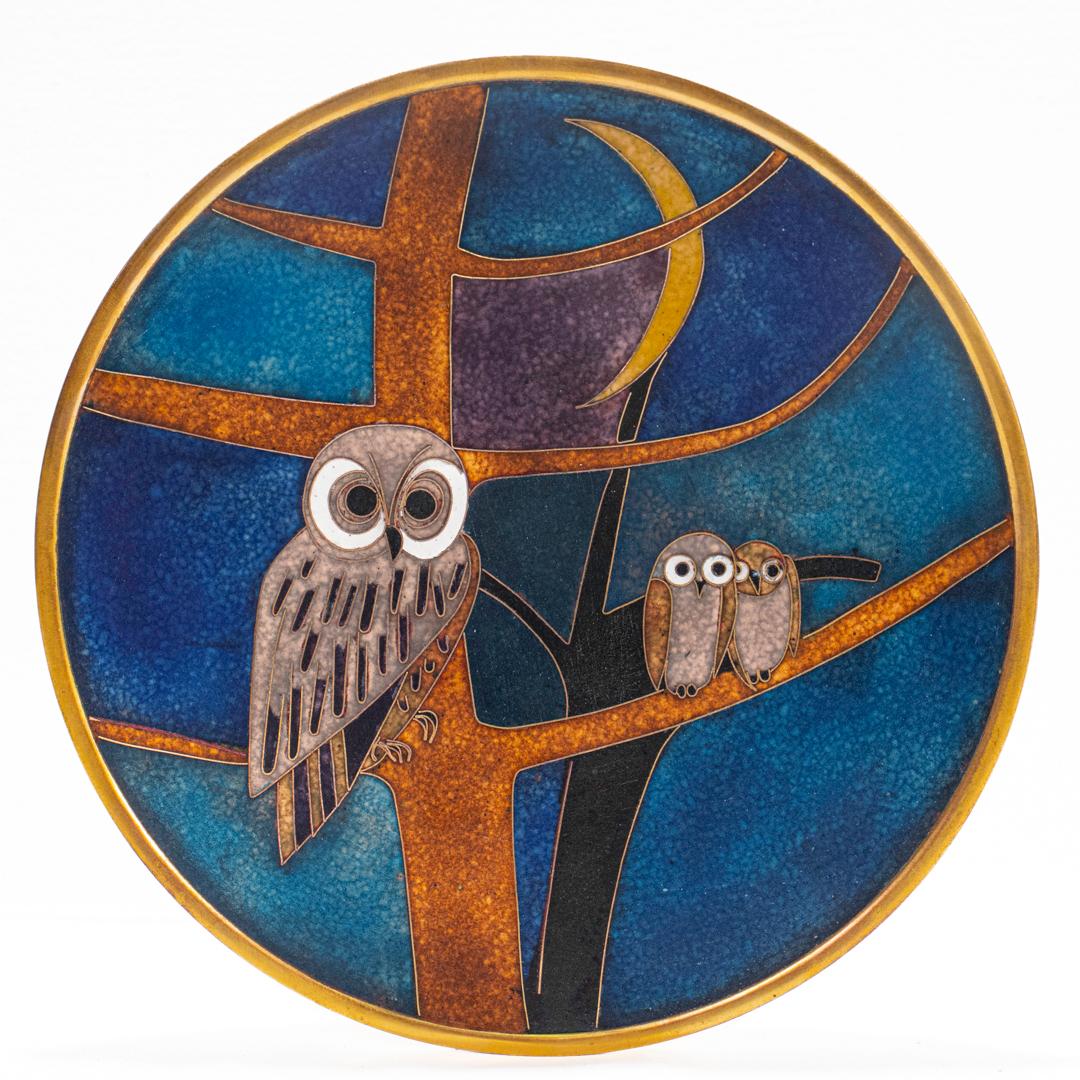 Un meraviglioso piatto in rame smaltato di piccole dimensioni della rinomata smaltatrice e creatrice di gioielli Käthe Ruckenbrod.

Decorato con smalti policromi.

Raffigurazione di una scena notturna con una madre gufo e due pulcini su un albero