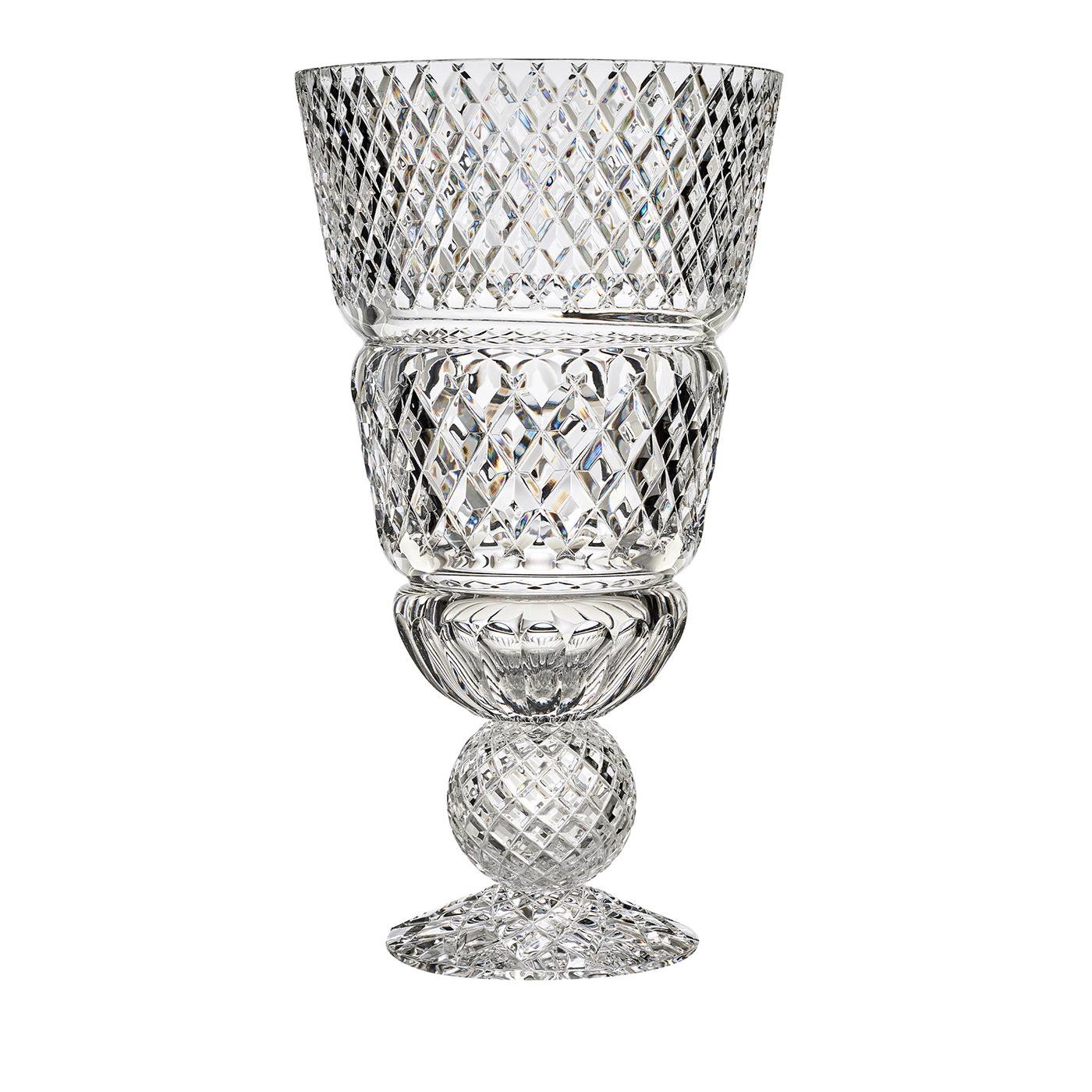 Vaso di dimensioni imponenti sostenuto da una base e da una sfera che può essere trasparente o ambrata per dare un tocco di colore. Il taglio a mano incrociato sulla superficie crea effetti di luce molto suggestivi. Artigianato e design diventano un