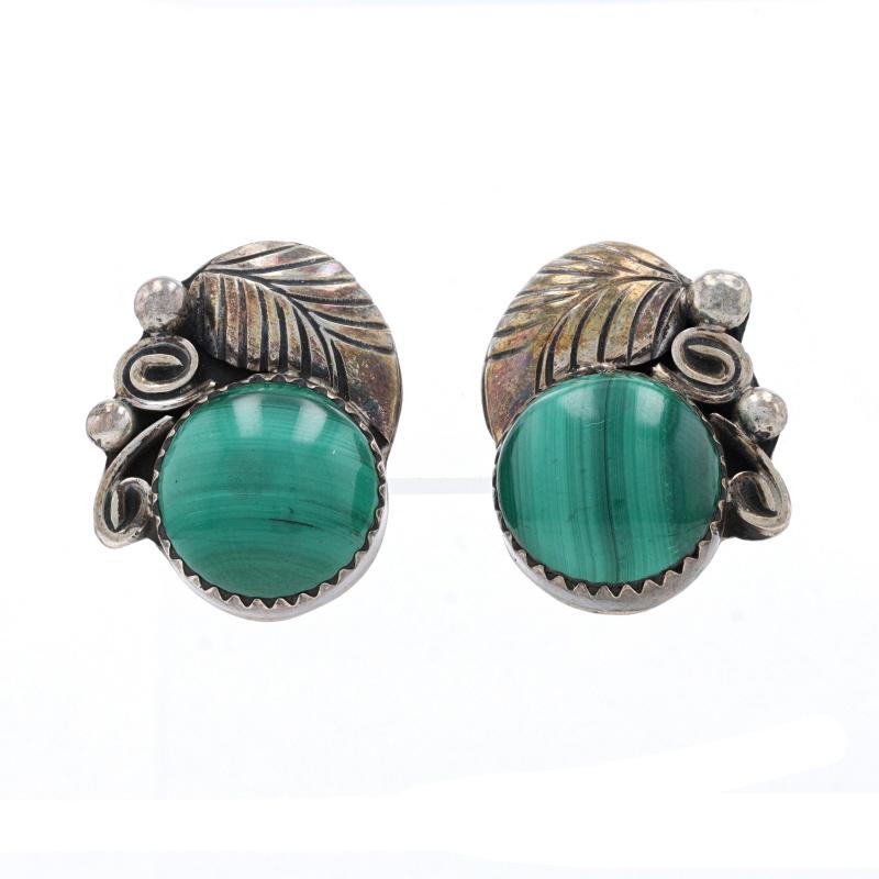 Native American
Artisan: Kathleen Chavez
Tribal Affiliation: Navajo
Design: Squash Blossom

Metal Content: Sterling Silver

Stone Information
Natural Malachite
Cut: Oval Cabochon
Color: Green

Earrings' Information
Style: Large Stud
Fastening Type: