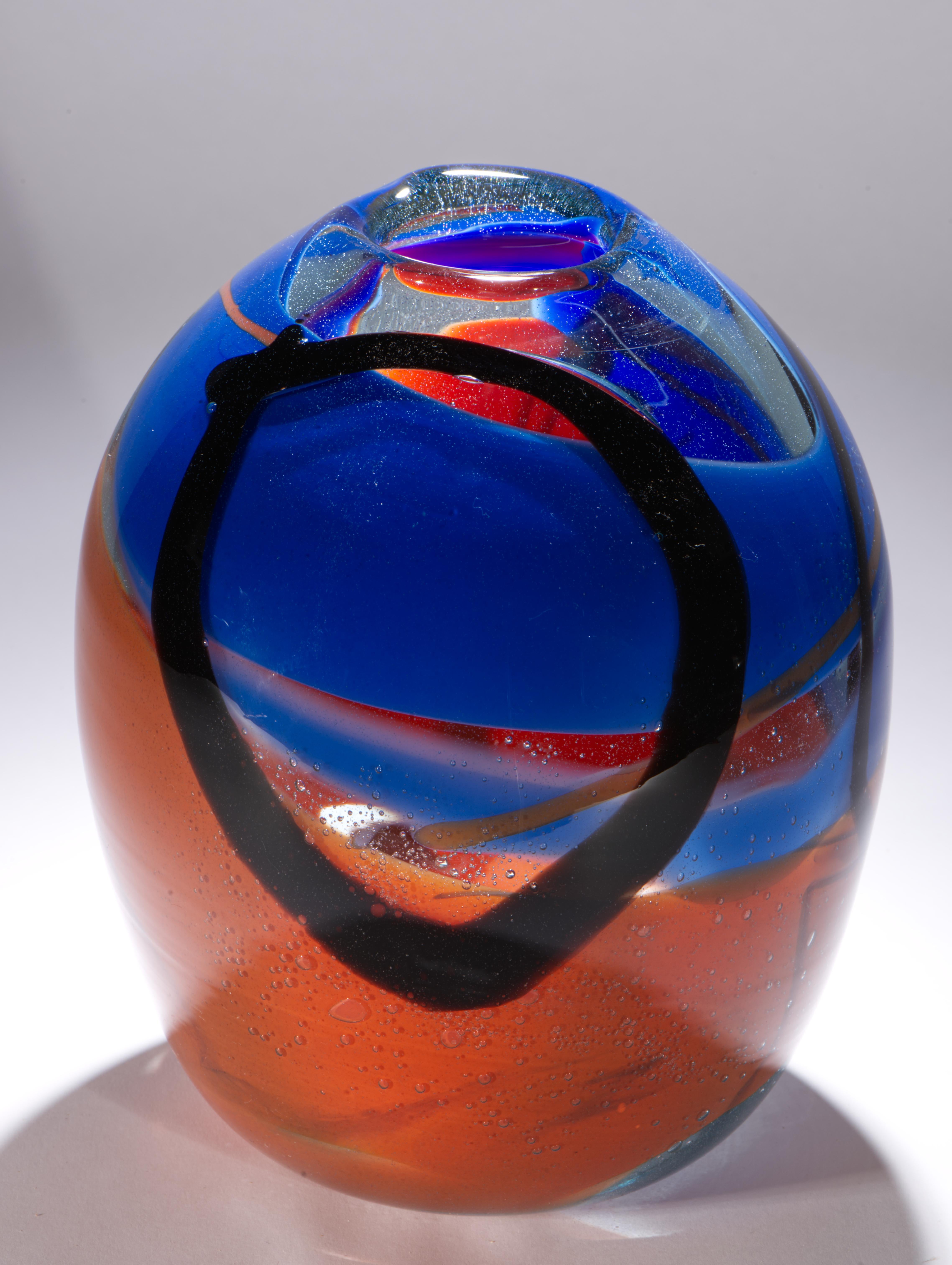 Il vaso d'epoca in vetro artistico soffiato a mano ha una forma ovoidale con apertura asimmetrica e una composizione multicolore di motivi in vetro blu zaffiro o cobalto, arancione bruciato e nero stratificati in vetro trasparente con la tecnica del