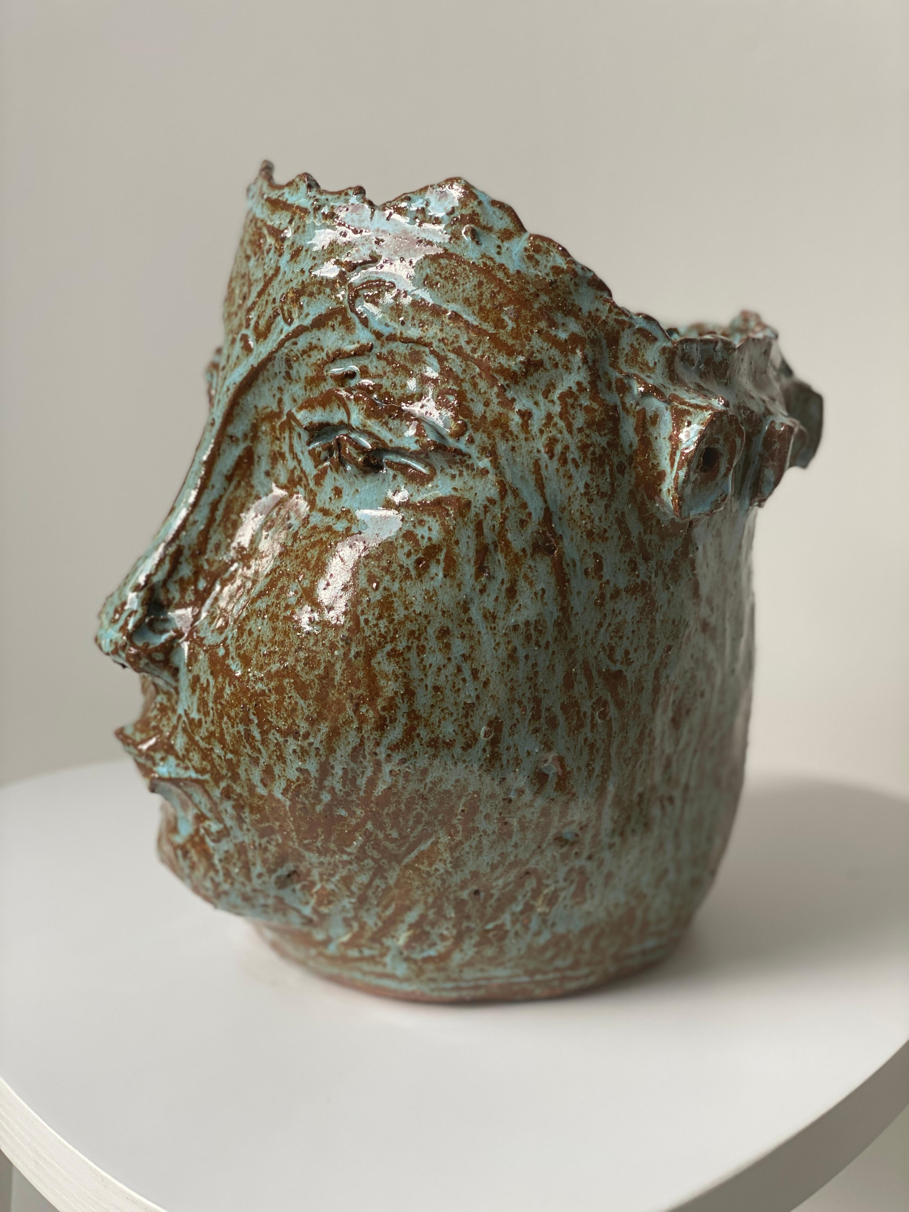 Elevate your space with this extraordinary exquisite clay sculptured face and head vase creation that promises to captivate and inspire.

This extraordinary, handcrafted vessel, radiates shinny aqua hues, earthy sienna and terracotta tones and