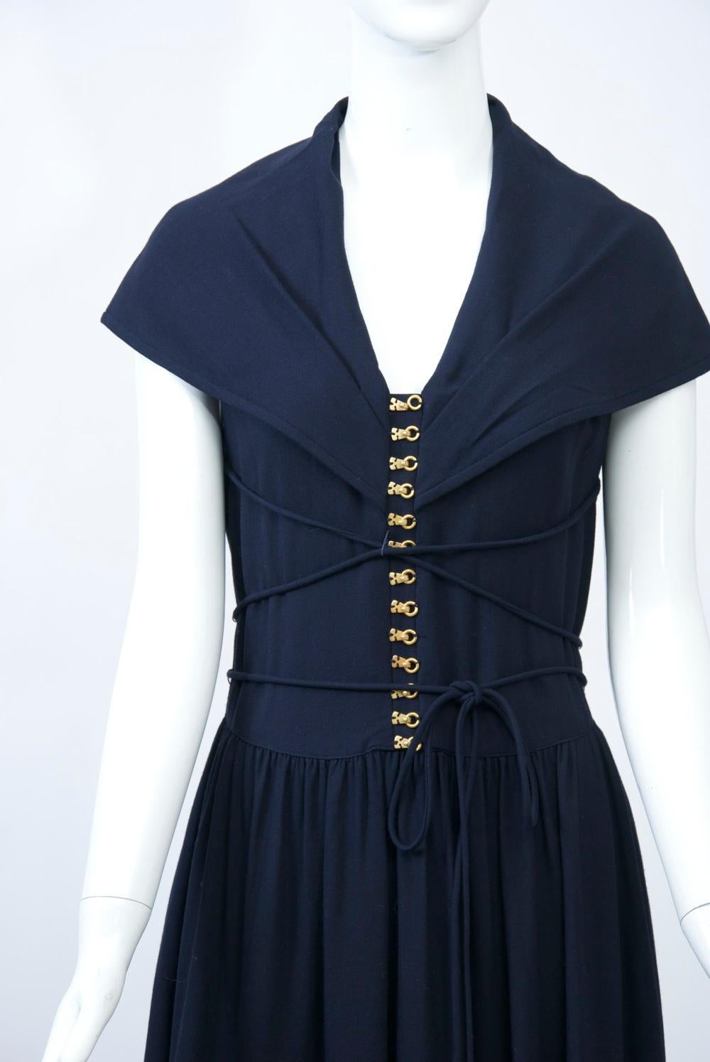 Long dress in navy wool/acrylic blend featuring a long torso with metal skate hooks laced with narrow self belt, and a large sailor collar that covers the upper arms and descends to a deep V in back. The gathered long skirt begins high on the hip.