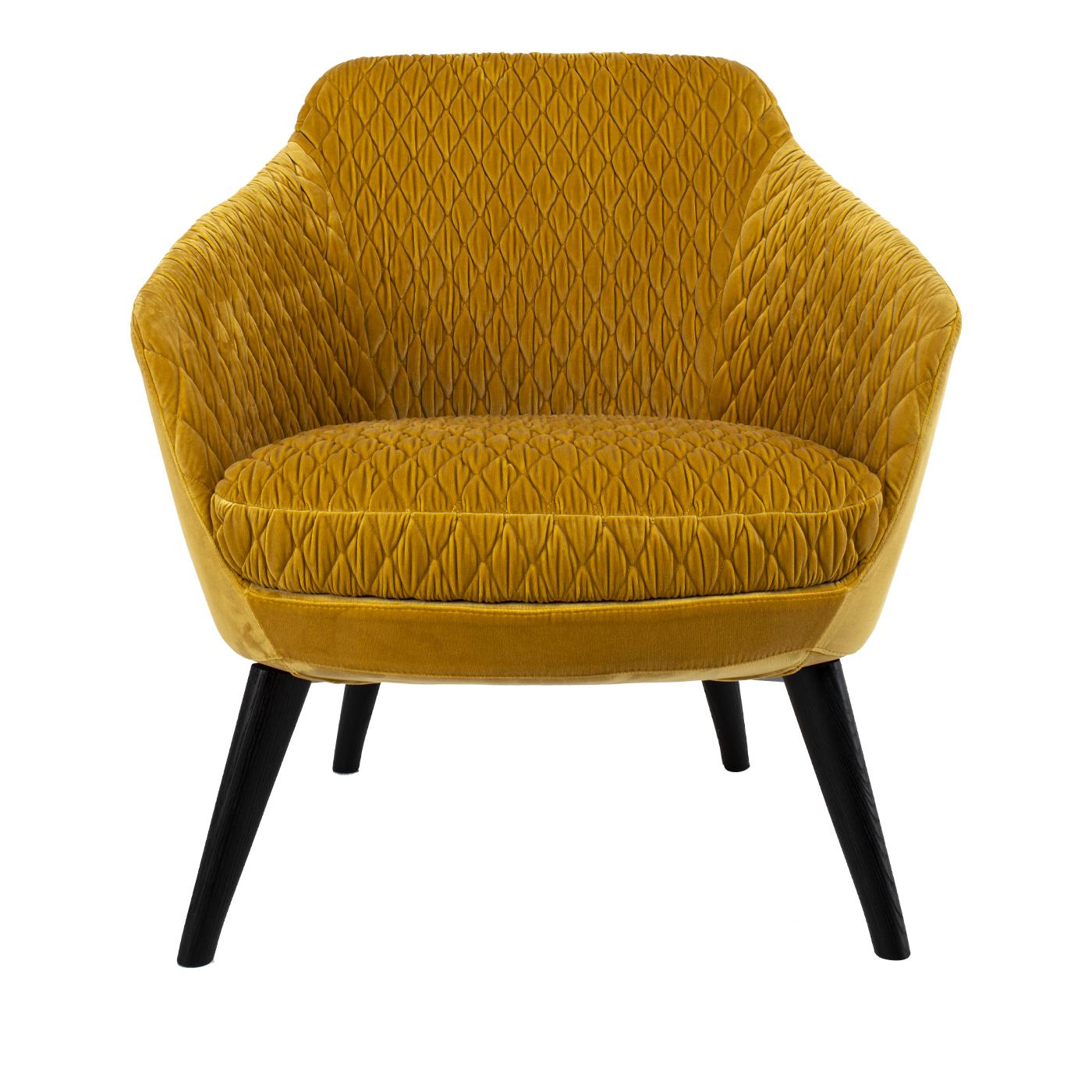 Loosen up and relax on the luxurious Katy armchair. The backrest and the seat cushion are covered in finely embroidered mustard yellow velvet, and the chair is supported by four black angled tapered metal legs. This versatile and unique product is