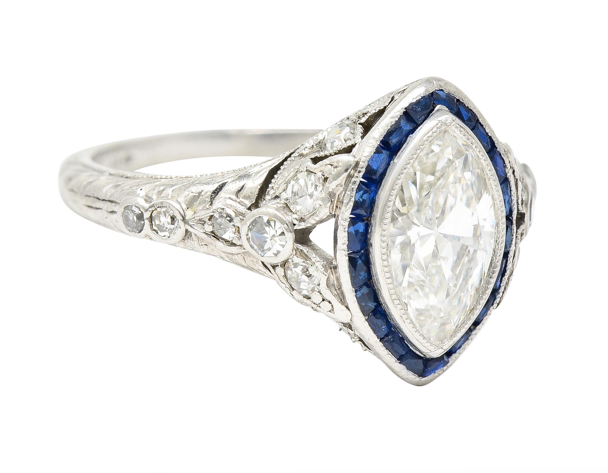 Centering a marquise cut diamond weighing approximately 0.90 carat total - I color with VS1 clarity. Bezel set with a halo surround of French cut sapphires weighing approximately 0.60 carat total. Transparent medium-dark blue in color - channel set