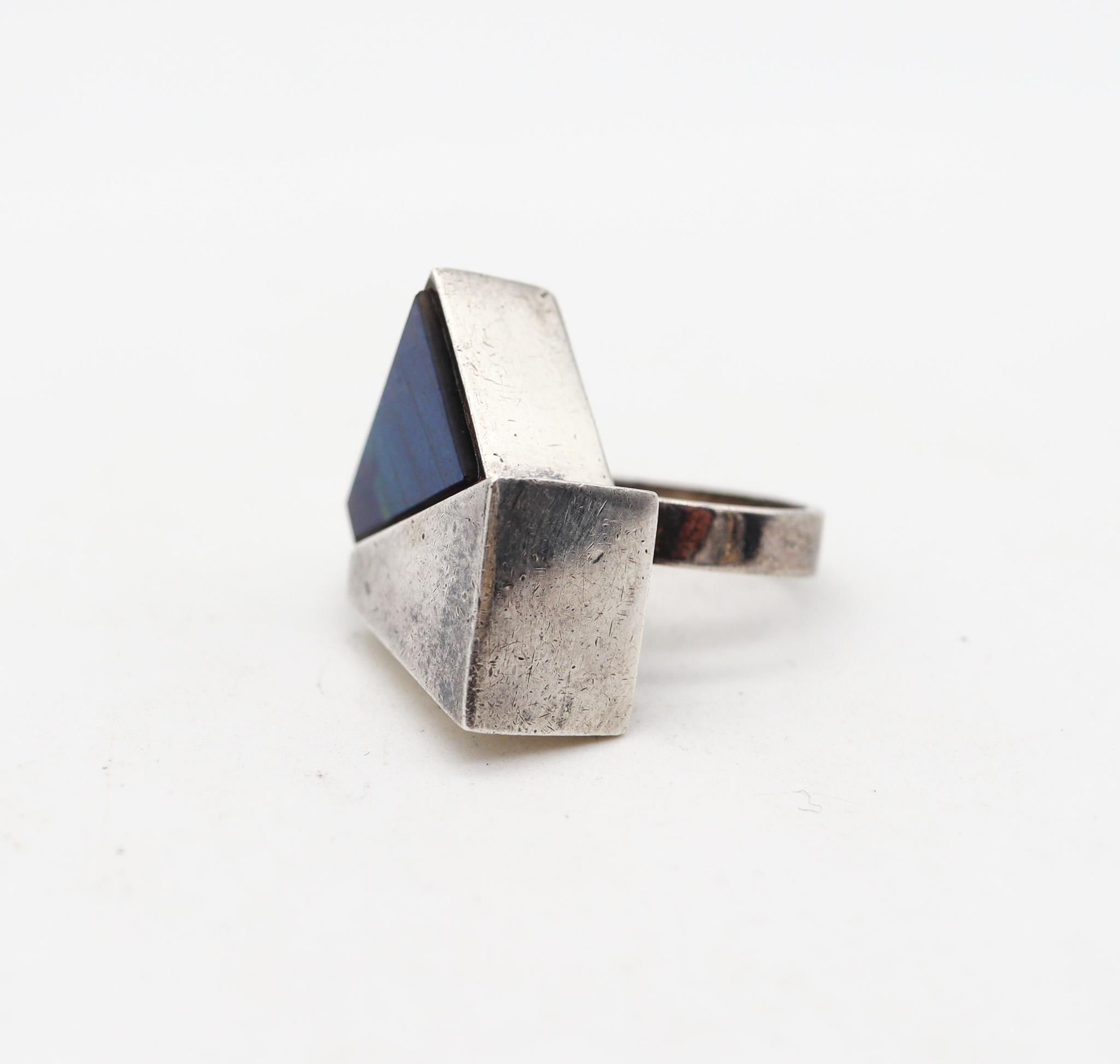Geometric ring designed by Kaunis Koru.

Absolutely beautiful modernist ring, created in Helsinki Finland by Kaunis Koru, back in 1974. Designed as a toi et moi ring, with two geometric trapezoids in .925/.999 solid sterling silver with high