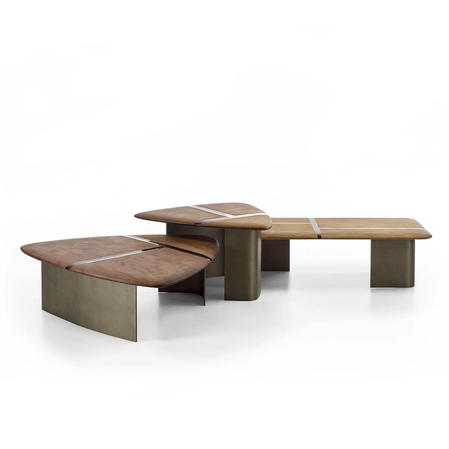 Small tables with a top made by juxtaposing Kauri wood parts with resin inserts, which, put together, create dynamic, refined geometries, and paired with an iron base, available in two heights. The thin thicknesses, achieved thanks to the bevelled