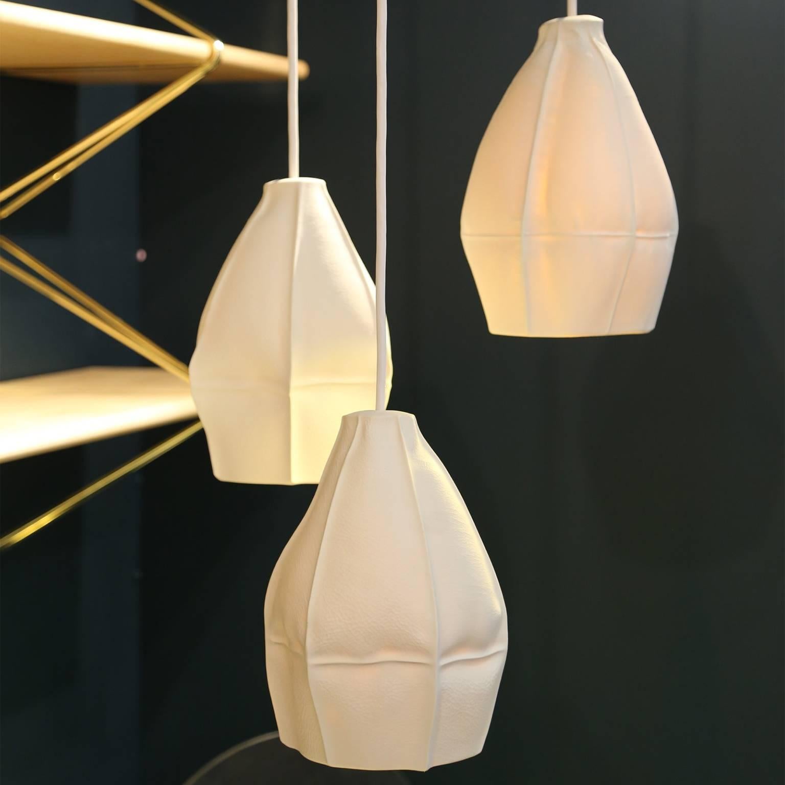 Souda's Kawa pendant lights are slip cast porcelain directly into dozens of leather molds resulting in highly-unique ceramic shades. The finalized pendant lights are dynamic and highly-unusual, emitting a soft glow that works well individually or in