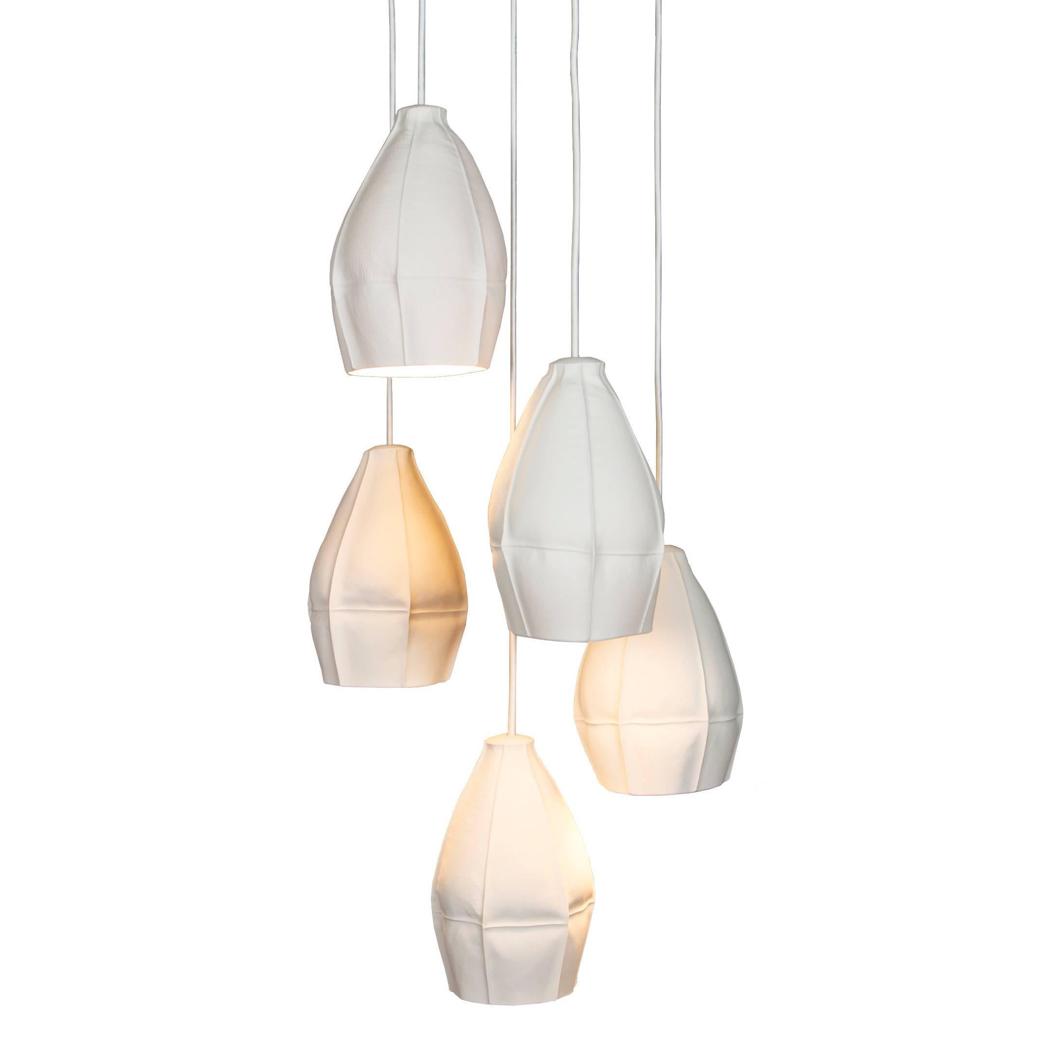 Les lampes suspendues Kawa de Souda sont des porcelaines coulées directement dans des douzaines de moules en cuir, ce qui permet d'obtenir des abat-jours en céramique très uniques. Les lampes suspendues finalisées sont dynamiques et très