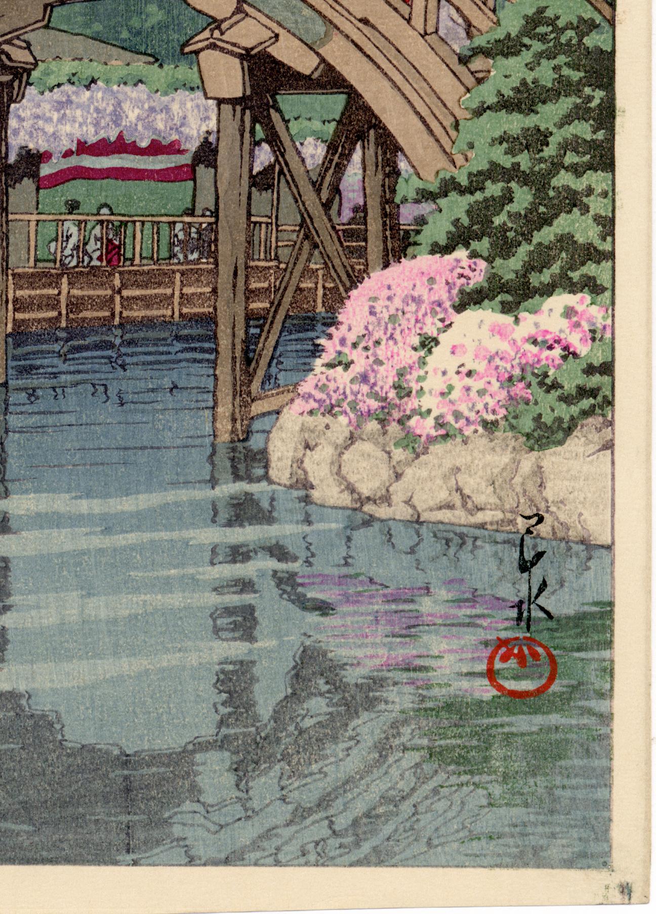 First edition original Japanese Color Woodblock print, printed in 1932. Famous view of the wisteria blooming at Kameido Tenjin Shrine. A brightly-dressed young girl has stopped atop the famous half-moon bridge., seeming to regard the viewer. In the