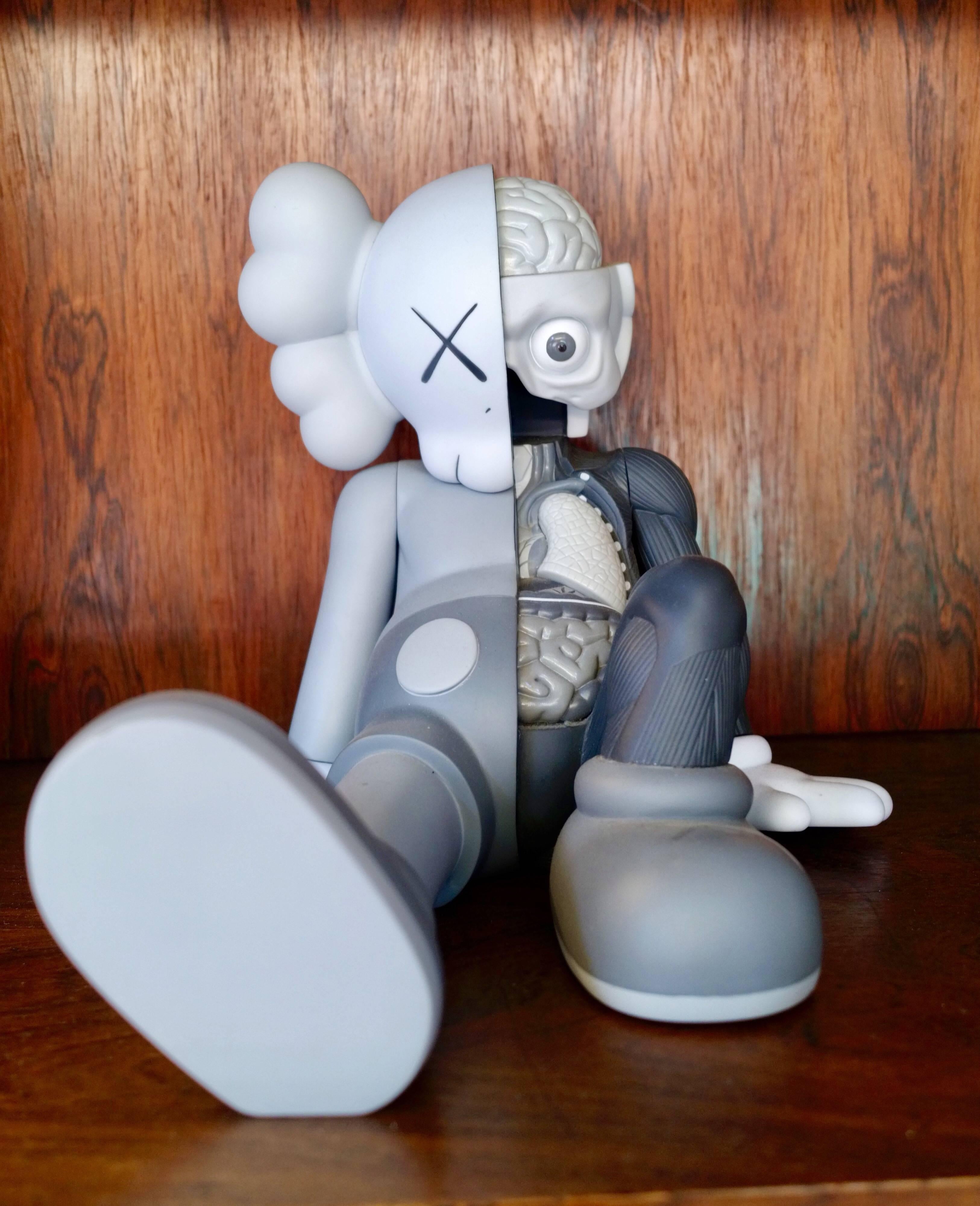 Kaws, resting place companion, 2013.
OriginalFake.

White and two different greys.
Painted cast vinyl.
From an edition of 1000.
In its original packaging / box. 
Produced and manufactured Medicom Toy Corporation, China.

About the artist: