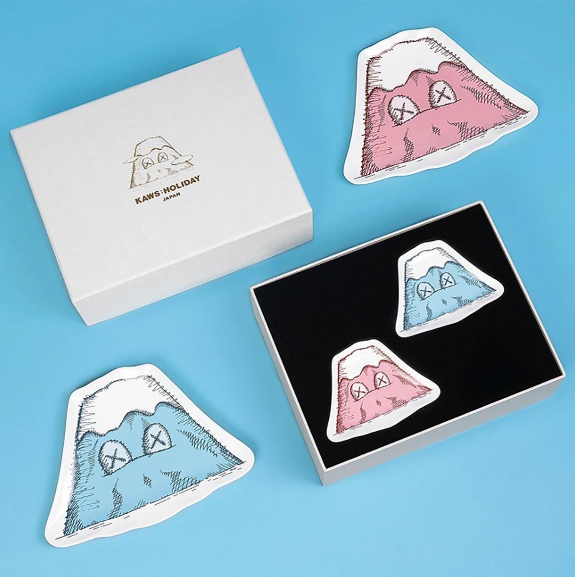 KAWS: HOLIDAY JAPAN Mount Fuji Ceramic Plate Set (Set of 4):
This standout KAWS ceramic plate set was published by All Rights Reserved to commemorate the debut of KAWS’ 40-meters-long figure placed amidst the quaint backdrop of Mount Fuji; set up at