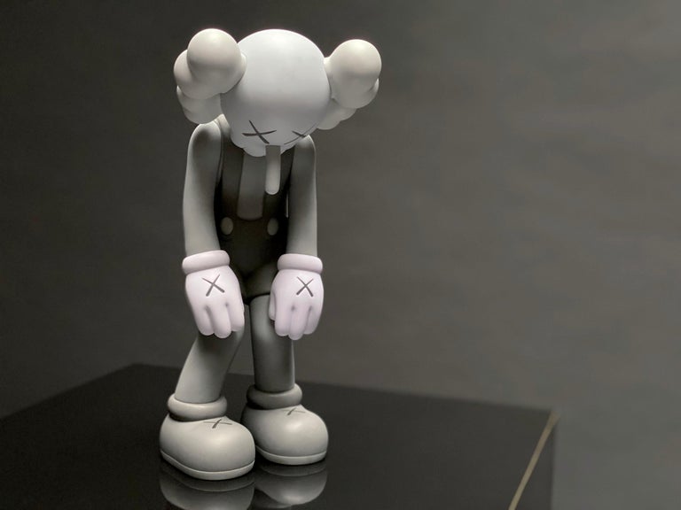 The 'Small Lie' vinyl art toy in greyscale was created in 2017 by KAWSONE. Among KAWS’s signature 'Companion' series, the 'Small Lie' has a childlike charm and instantaneous likability. Clad in overall shorts, the Pinocchio-inspired figure bows its