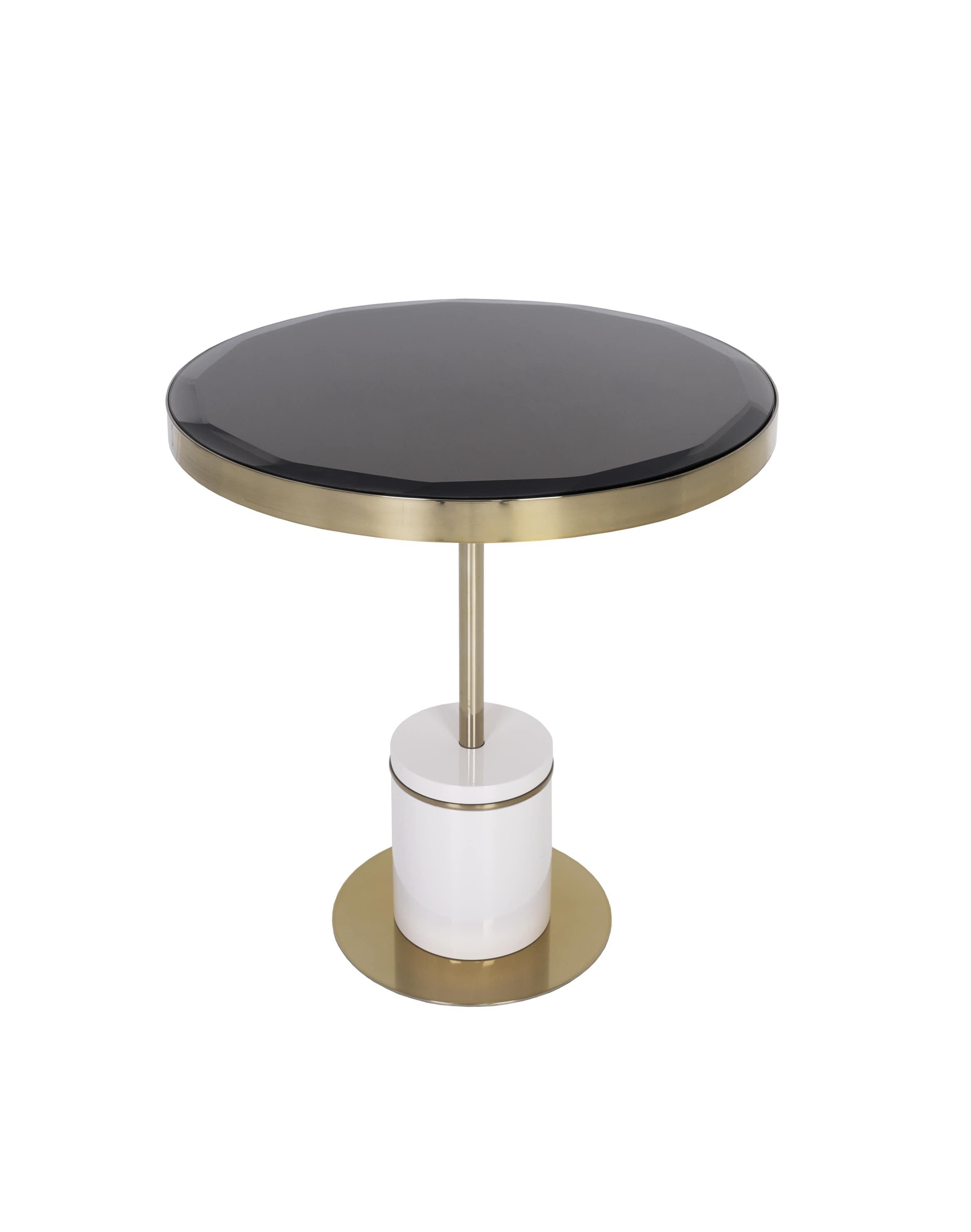 Étude d'équilibre et de contraste des matériaux, cette table d'appoint associe des finitions laquées, des détails métalliques et l'élégance subtile de son plateau en verre.La dualité des tons crée une présence architecturale saisissante, tandis que