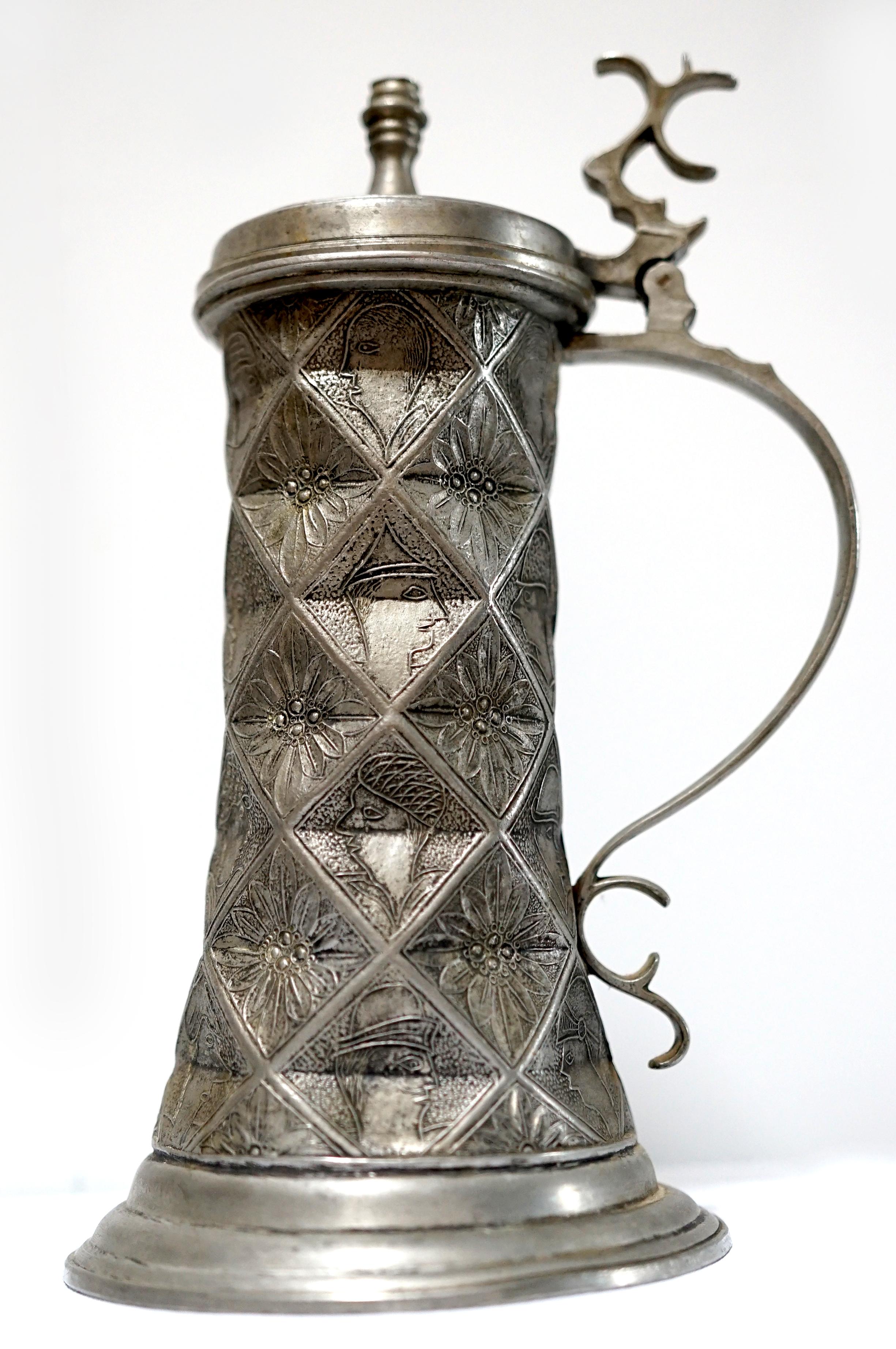 The Fein Zinn and Kayserzinn set is handcrafted pewter. The vintage Fein Zinn pewter tankard and cup is probably late 19th Century. 
Of circular section with shouldered cover, shaped handle and thumbmold, flaring body with geometric 