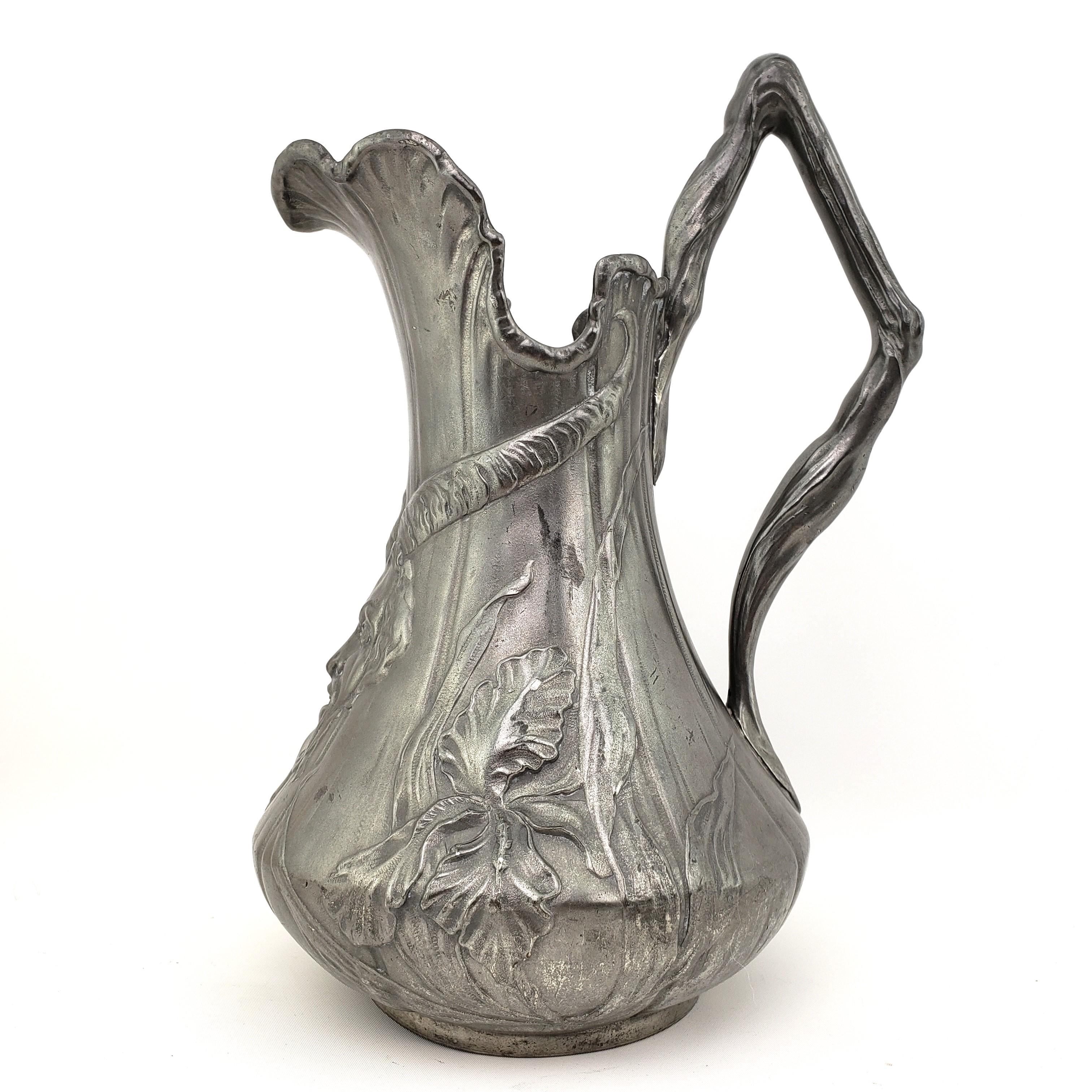 German Kayserzinn pewter wine/water pitcher or jug with Art Nouveau style low relief iris decoration centered by a Devils head under the spout and a handle designed as a vine branch.