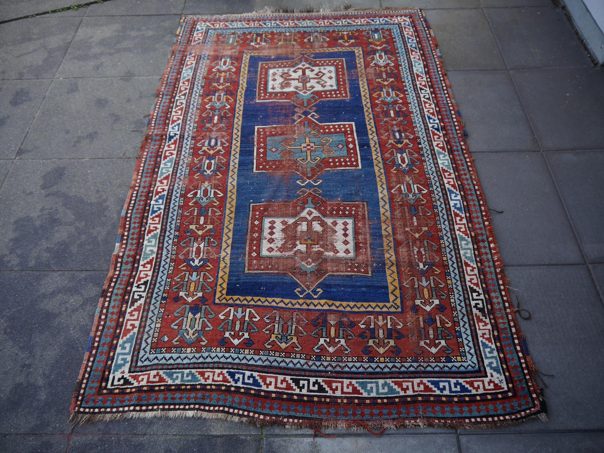 A mall sized Kazak rug from Azerbaijan with geometric design. The pile is made of wool - hand spun, hand dyed with all vegetable dyes and knotted by women in a tribal style. The rug is very decorative, the condition is distressed with the looked