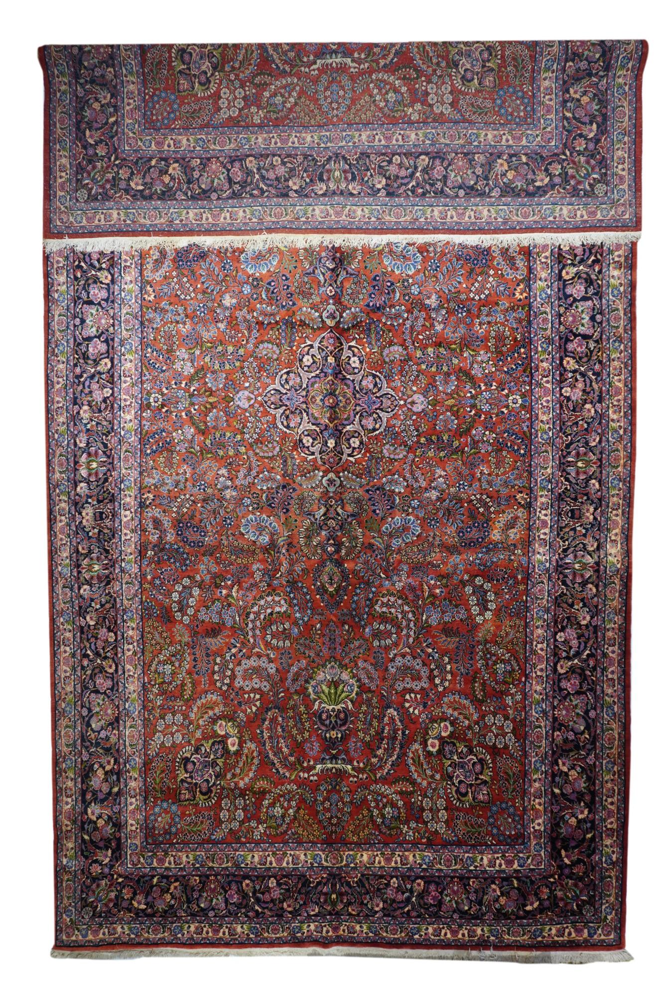Ce tapis de ville de l'ouest de la Perse, en bon état et sur fond rouge, présente un motif de 