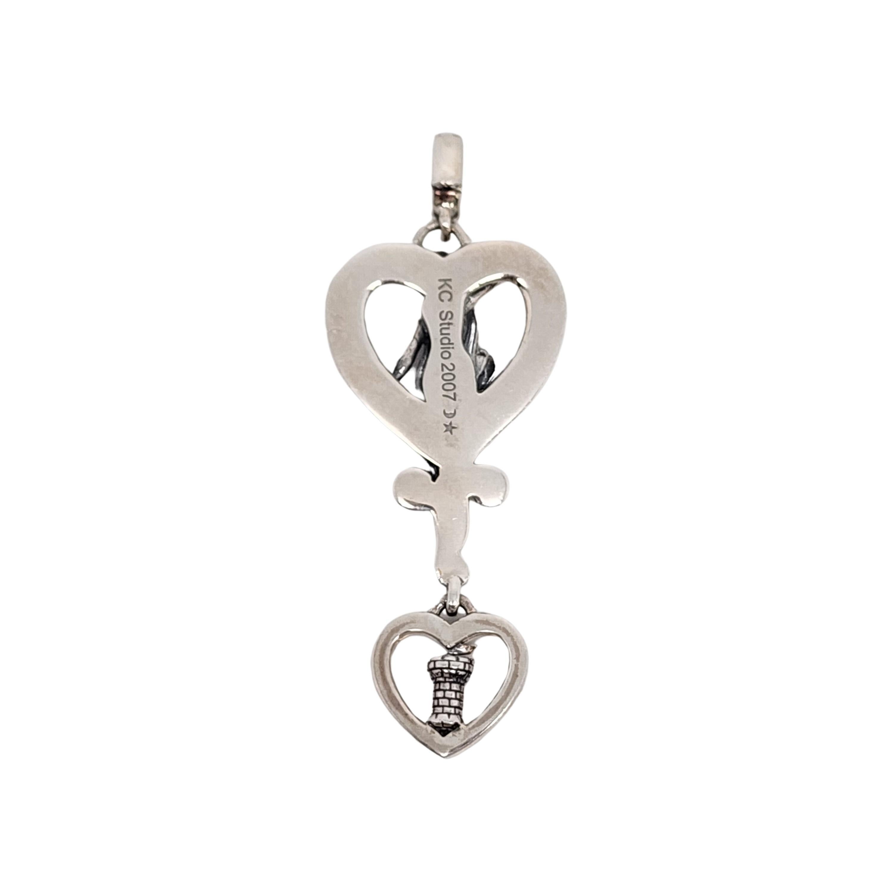 KC Studio sterling silver Rapunzel Love pendant by designer Barry Kieselstein-Cord.

This Rapunzel pendant features a woman with long hair in the shape of a heart around her. A smaller heart dangles with a small castle at its center with different