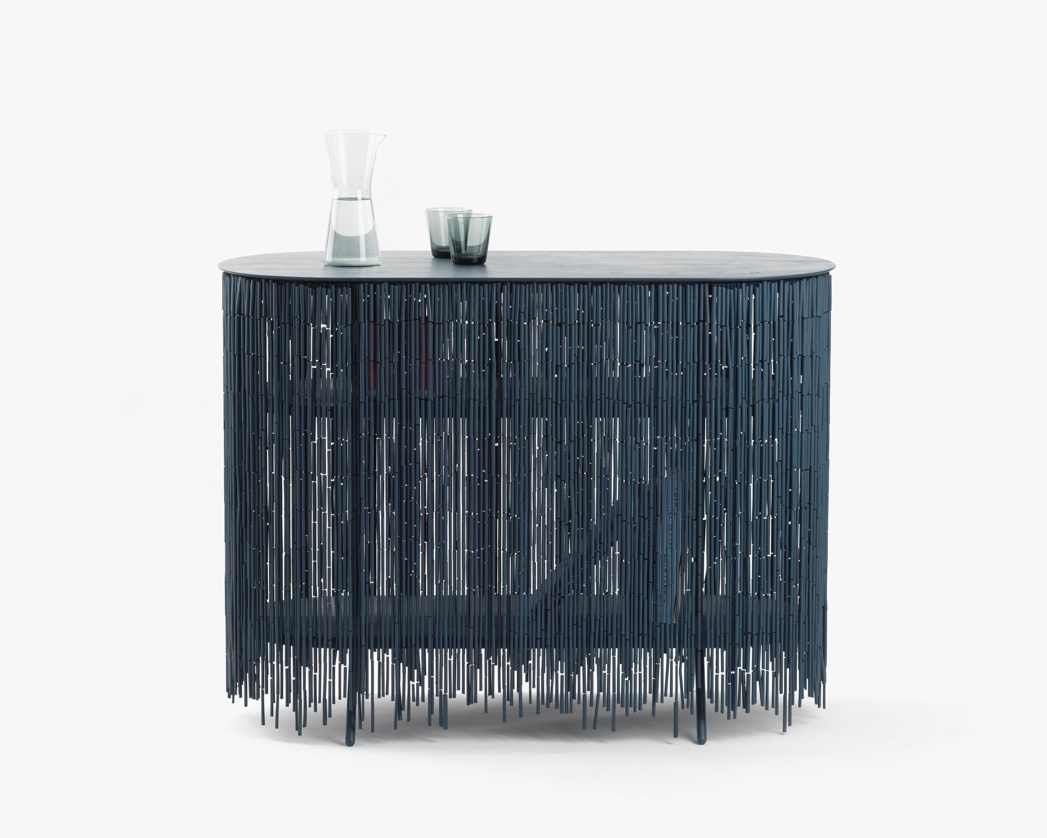 Keefer is a credenza that alludes to the objects stored within its shelves, yet obscures their identity through its bamboo-beaded skirt. The skirt masks the vertical supports, creating the illusion of floating shelves. The interior can be accessed