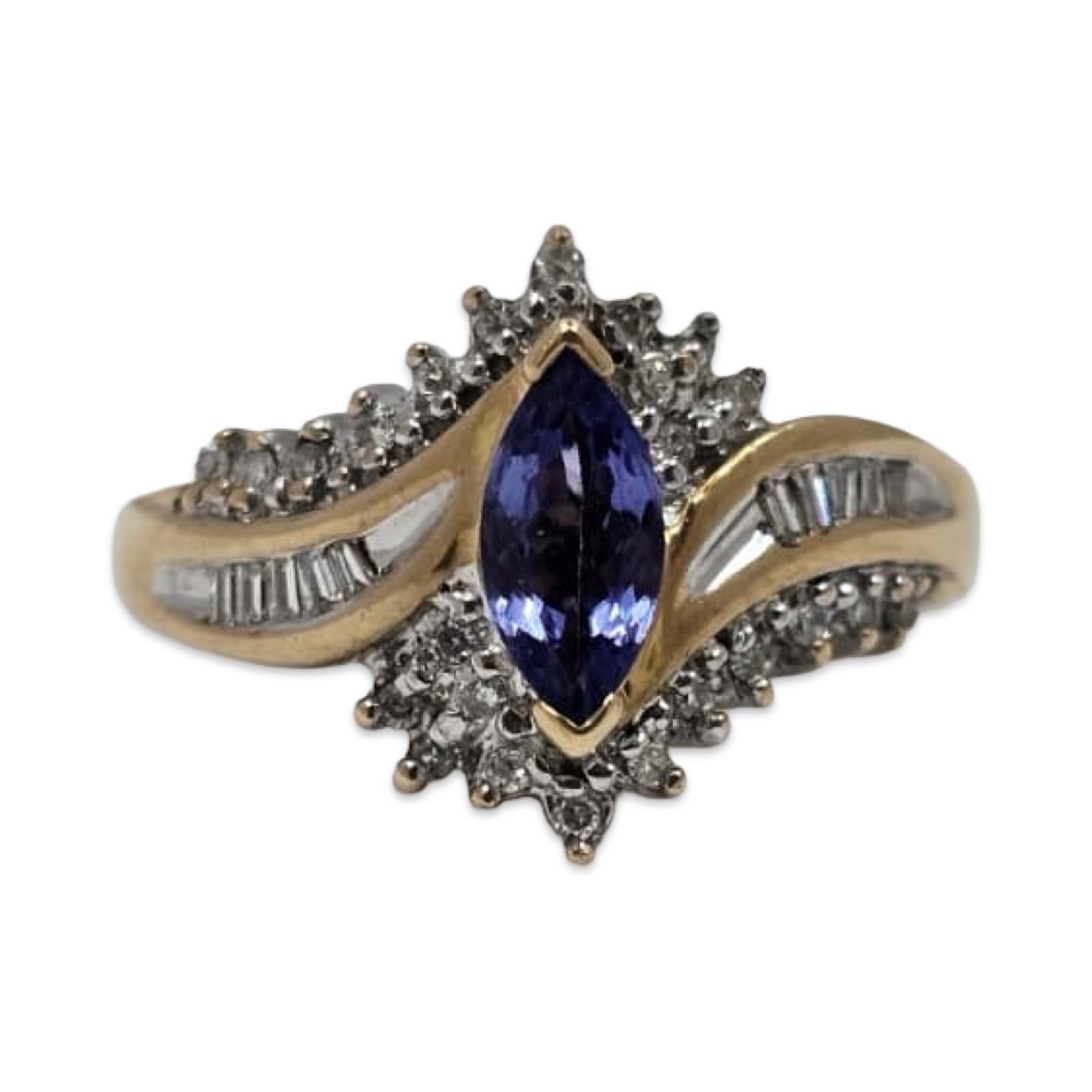 Anello Keepsake Diamond Rings in oro 14K con una tanzanite marquise di circa 0,50 carati che misura 9 × 4 mm, completata da circa 0,46 carati di diamanti rotondi e baguette. Il design fluente a spalla divisa crea un'elegante onda di diamanti intorno