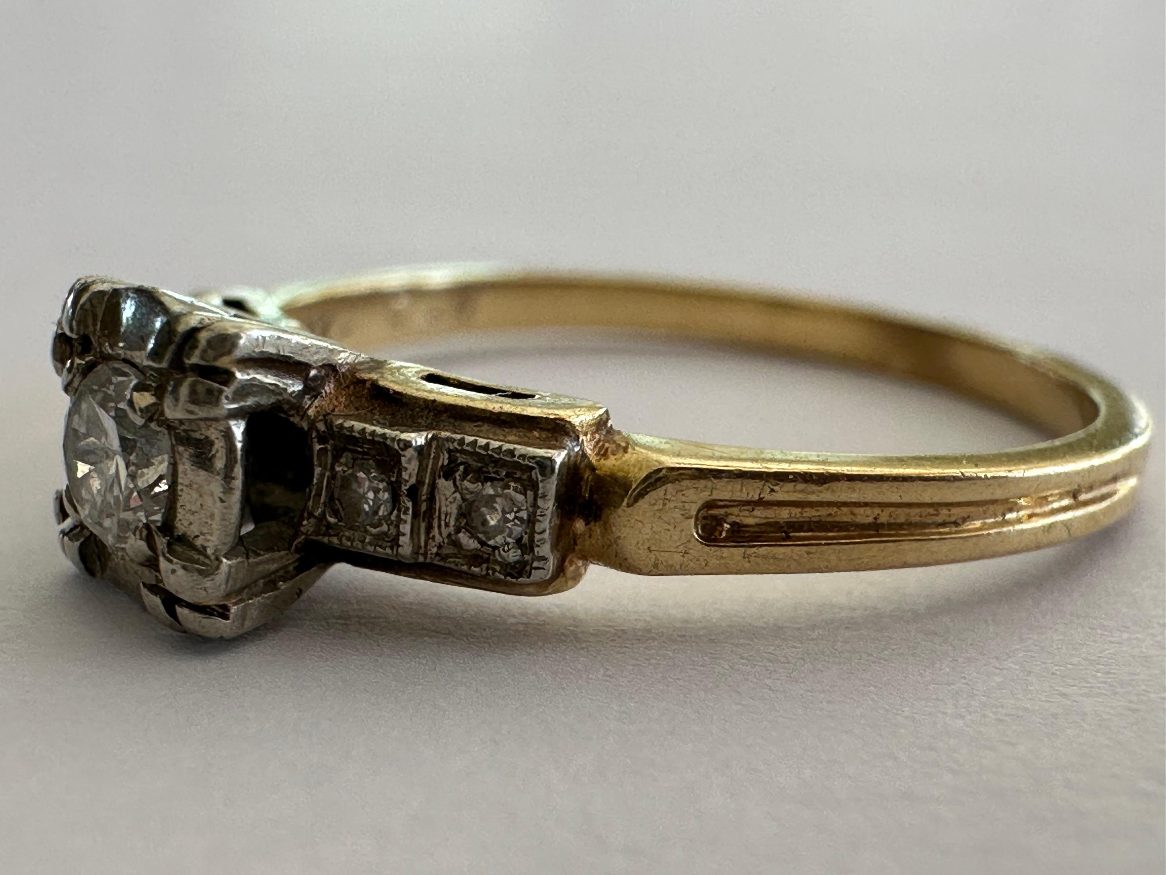 Ein Diamant im Old-European-Schliff mit einem Gewicht von ca. 0,10 Karat, Farbe F, Reinheit VS, steht im Mittelpunkt dieses Schmuckstücks aus der Mitte des Jahrhunderts, das mit vier Diamanten im Einzelschliff, zwei auf jeder Seite, akzentuiert ist,