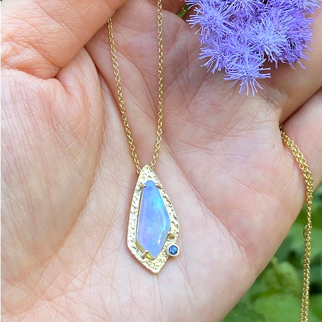 Keiko Mita's unique Azure Necklace features an Australian Crystal Opal (2.51 Carats) set in a 14 Karat Yellow Gold frame accented with a Blue Sapphire (0.035 Carats). The contemporary pendant, wihch is 22 mm long and 11 mm wide, is presented on an