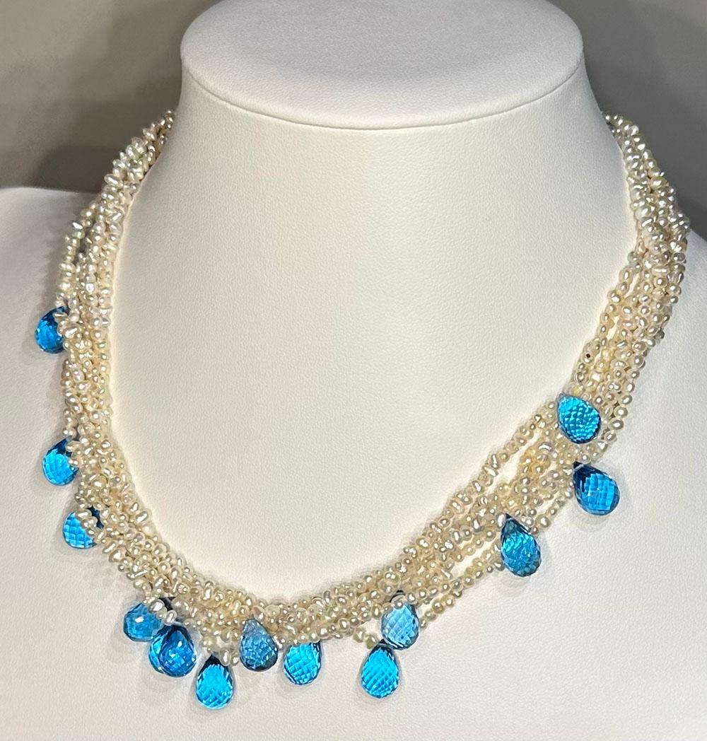A Luxurious Keishi Salt Water Pearl Torsade Necklace with Topaz Briolettes. 86 Carats in 14 sky blue Topaz Briolettes interwoven in 7 strands of saltwater Keishi Pearls. A large silver clasp for ease of adornment on your person with this stunning