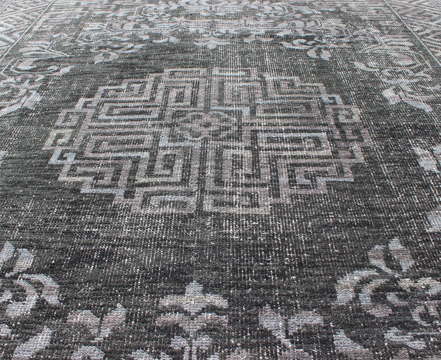 Keivan Woven Arts Modern Khotan Hand Knotted Wool Rug in Charcoal & Gray. This modern Khotan rug has been hand-knotted features an all-over, sub-geometric late central medallion design rendered in charcoal and gray tones. A complementary border