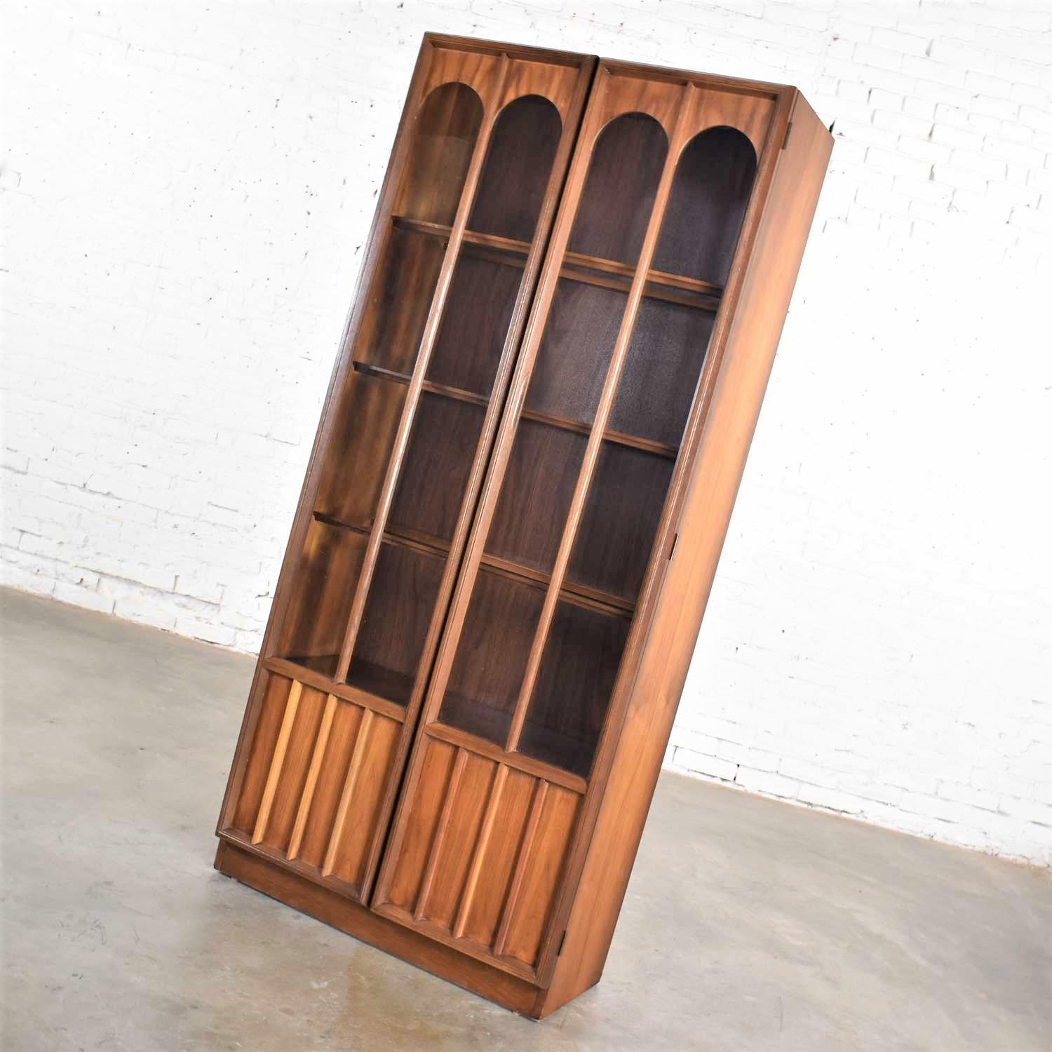 Handsome MCM aka Mid-Century Modern lighted display cabinet or bookcase attributed to Keller Furniture and in the style of Broyhill Brasilia or Kent Coffey. In wonderful vintage condition. Its dark wood finish is in beautiful shape. We did replace