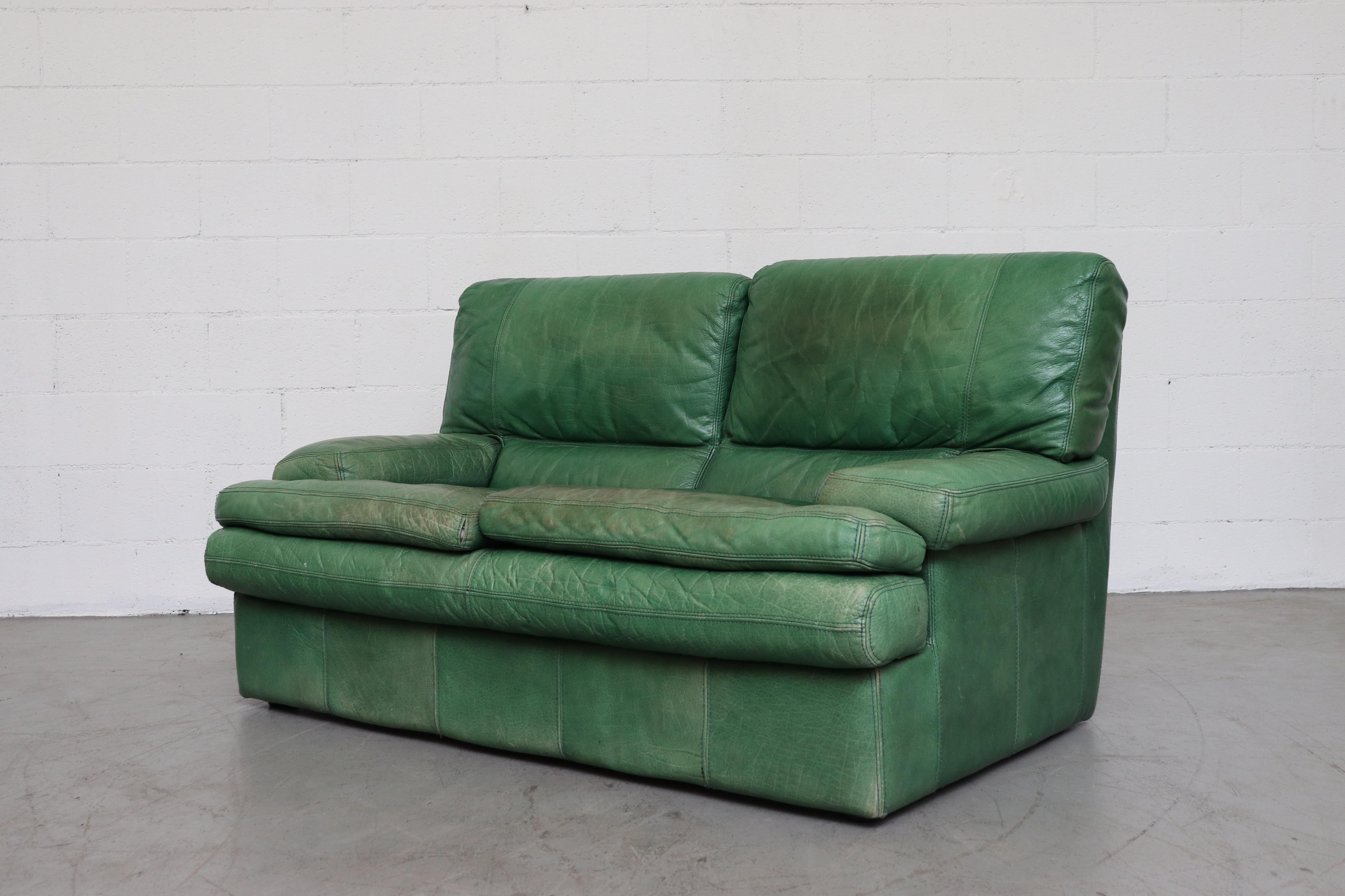 Kelly green leather love seat sofa. Well worn with visible wear and patina. In original condition with wear consistent with age and use.