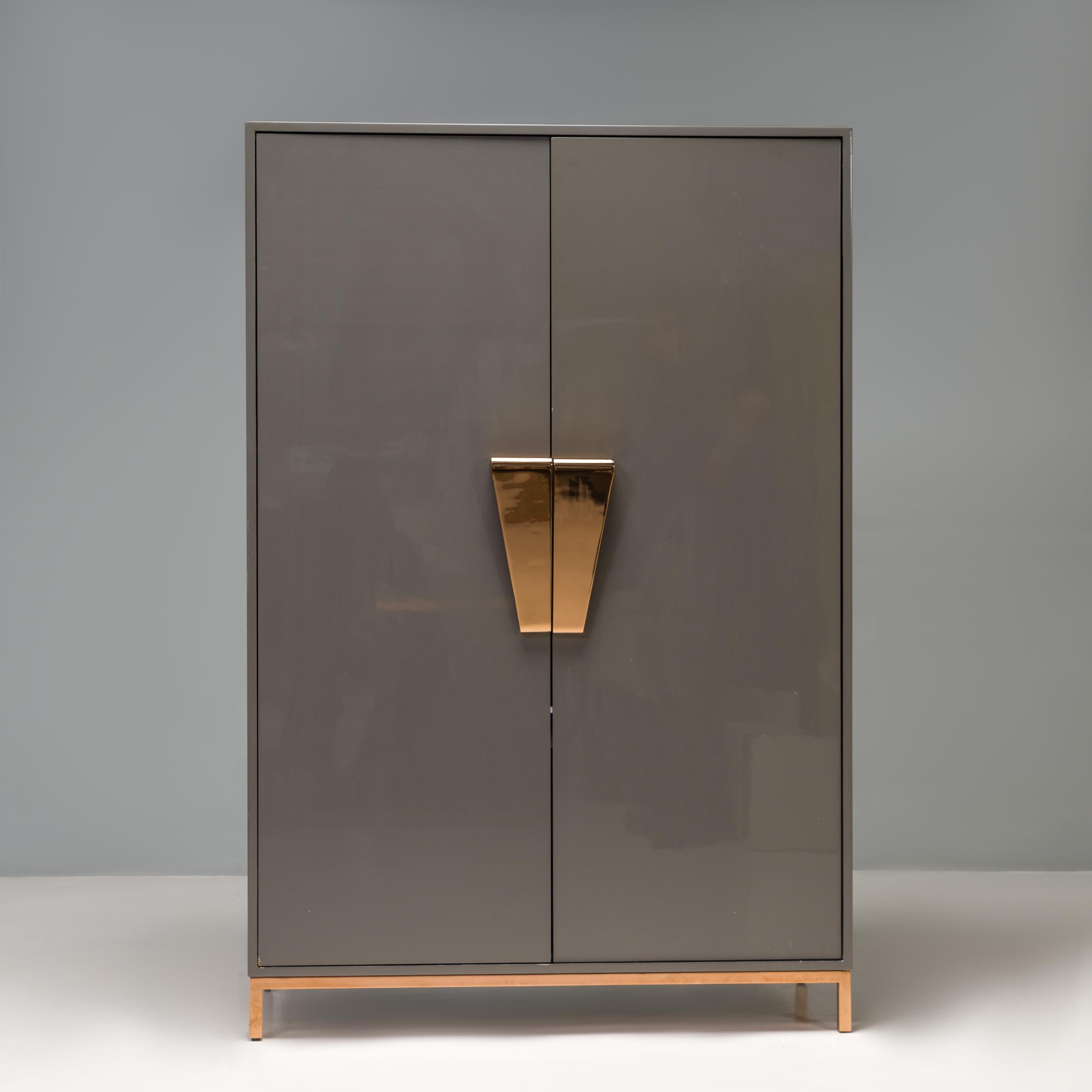 Conçue par la designer d'intérieur britannique Kelly Hoppen dans le cadre de sa gamme de meubles signature, l'armoire Shield offre une solution de rangement moderne et élégante.

Construit en bois laqué gris foncé, le meuble repose sur de fins pieds