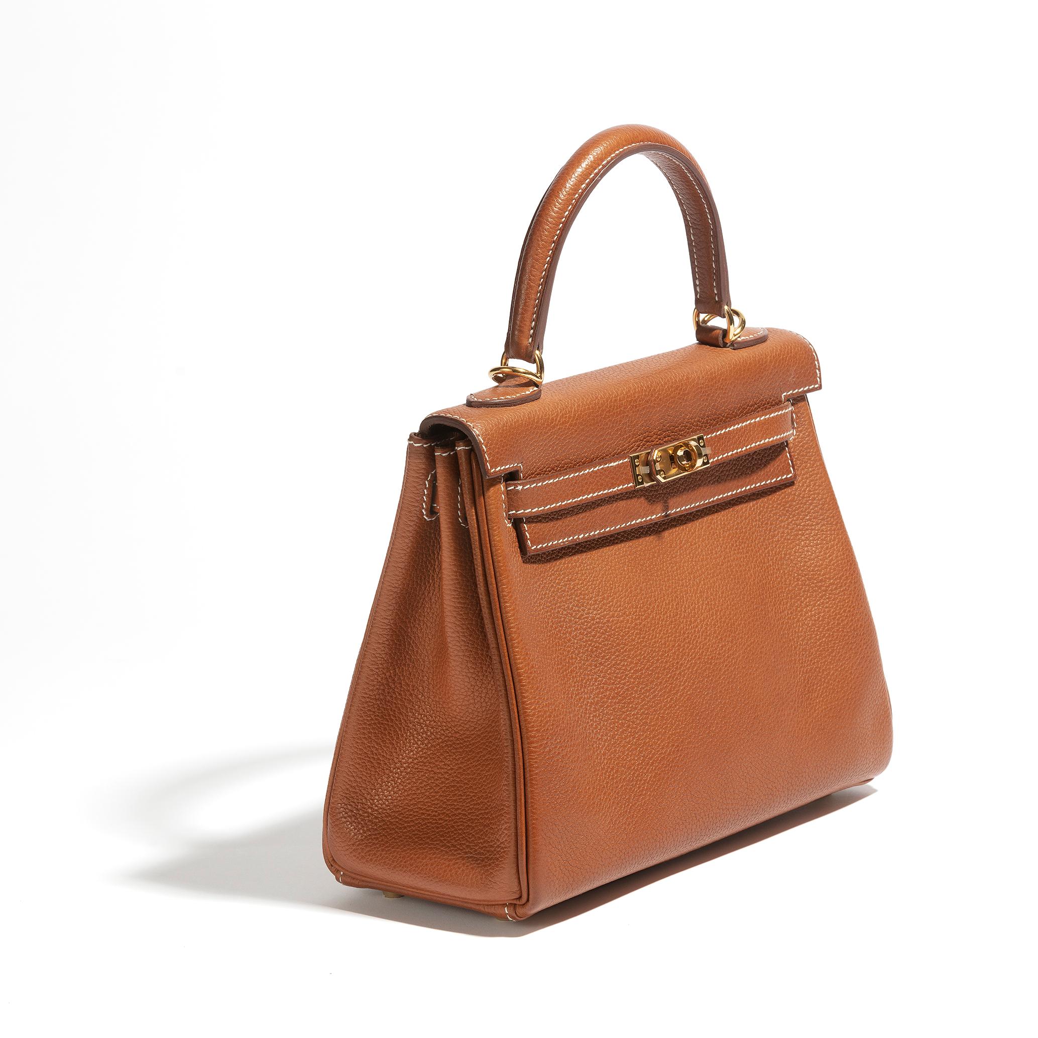 A stunning and rare collector's item, this is a 25cm retourne kelly in barenia faubourg, one of Hermès' most luxurious leather. A buttery tan hue, the fauve colour is particularly beautiful with the gold hardware, still with plastic protectors. The