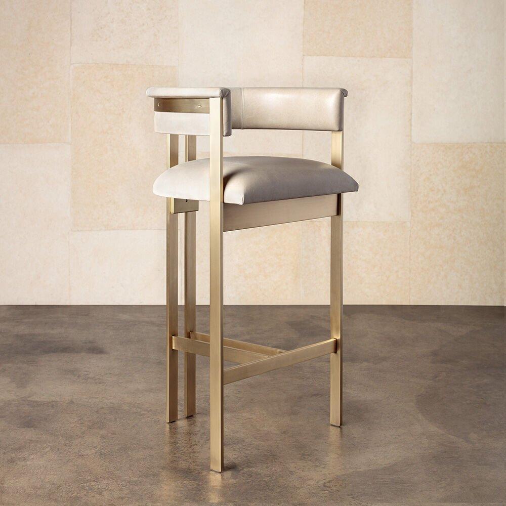 The iconic Elliot bar stool combines clean lines with classic vernacular. This upholstered stool features paired brass bar-stock legs finished in either a Burnished Brass or Oil Rubbed Brass finish. The seat is available in a selection of curated