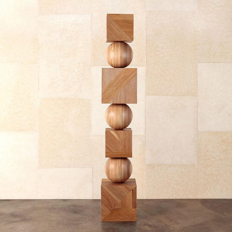 The Tephra Totem is an expertly crafted geometric floor standing sculpture executed in finely ribbed oak. Three turned-wood spheres in solid oak separate four boxes detailed with randomly applied angular panels of ribbed oak in a column towering