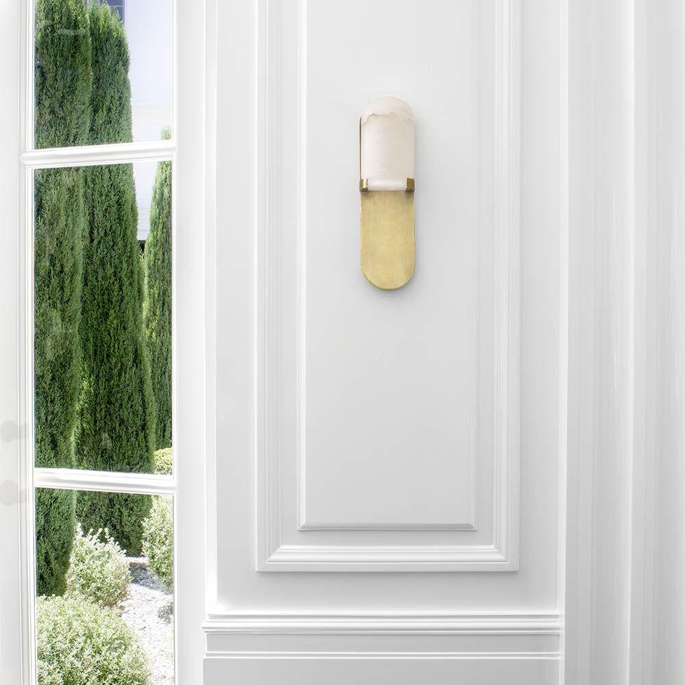 Effortlessly pairing natural alabaster and sleek metal detailing in a streamlined geometric form, the Melange Medium Elongated Pill Sconce exudes a modern refinement while emphasizing the beauty of natural stone. This sconce features hand-carved