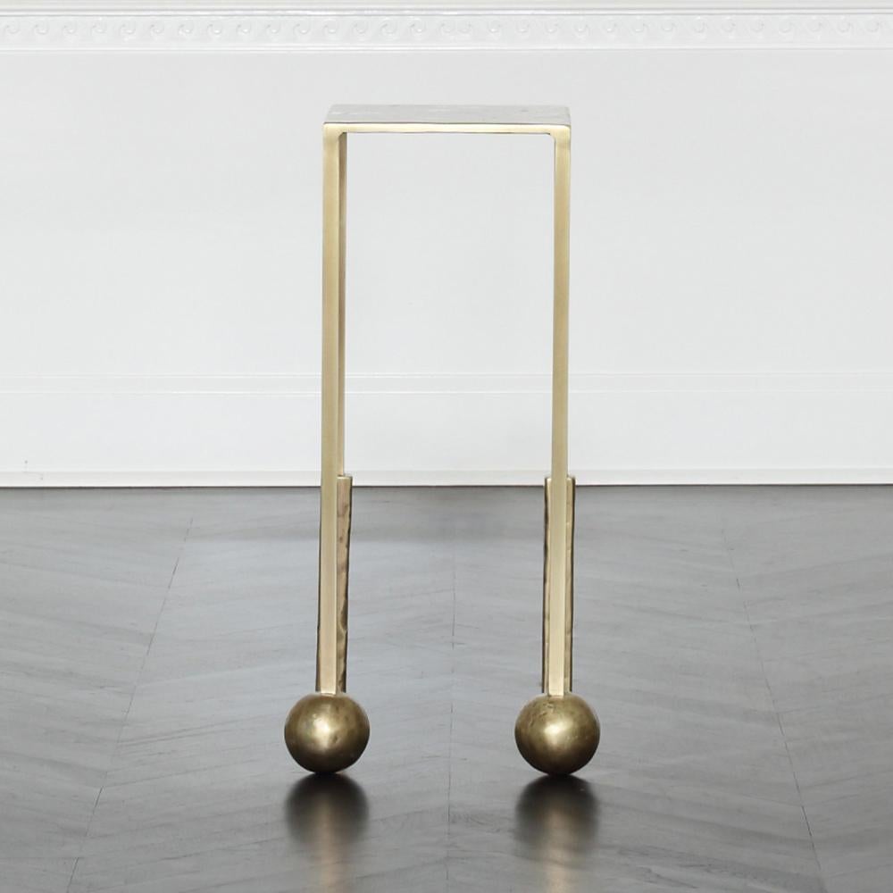 La table à cocktail Nimes Petite est moulée artisanalement dans de l'aluminium avant que notre finition brillante en laiton bruni ne soit appliquée, donnant à la pièce une texture sculpturale modelée et une sensation de solidité. La forme elle-même