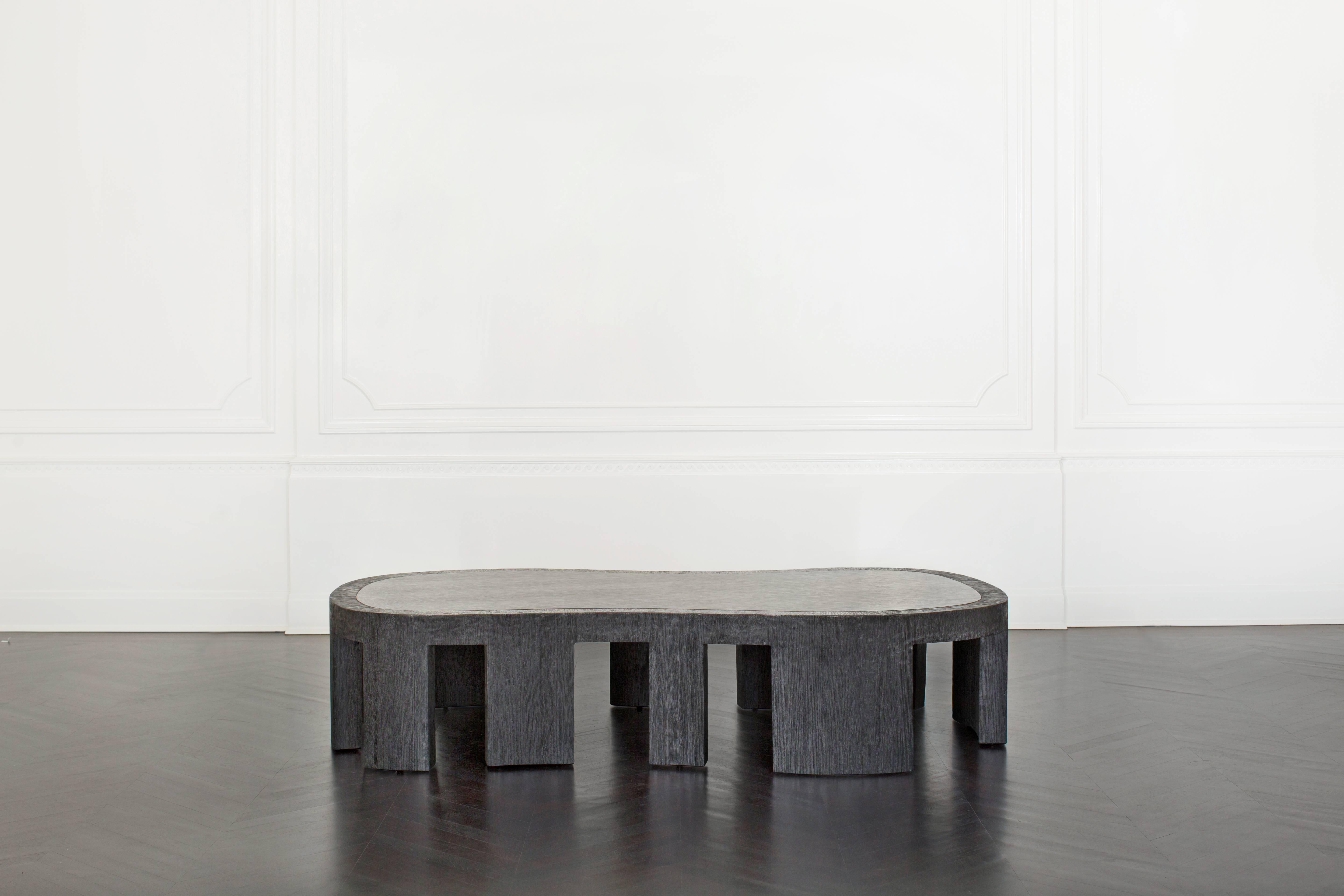 The boldly amorphous Rhodes coffee table features a monolithic ebonized and wire-brushed oak frame that subtly contrasts with the smooth surface of the solid quartersawn wood top and monolithic legs. Available in ebonized oak.