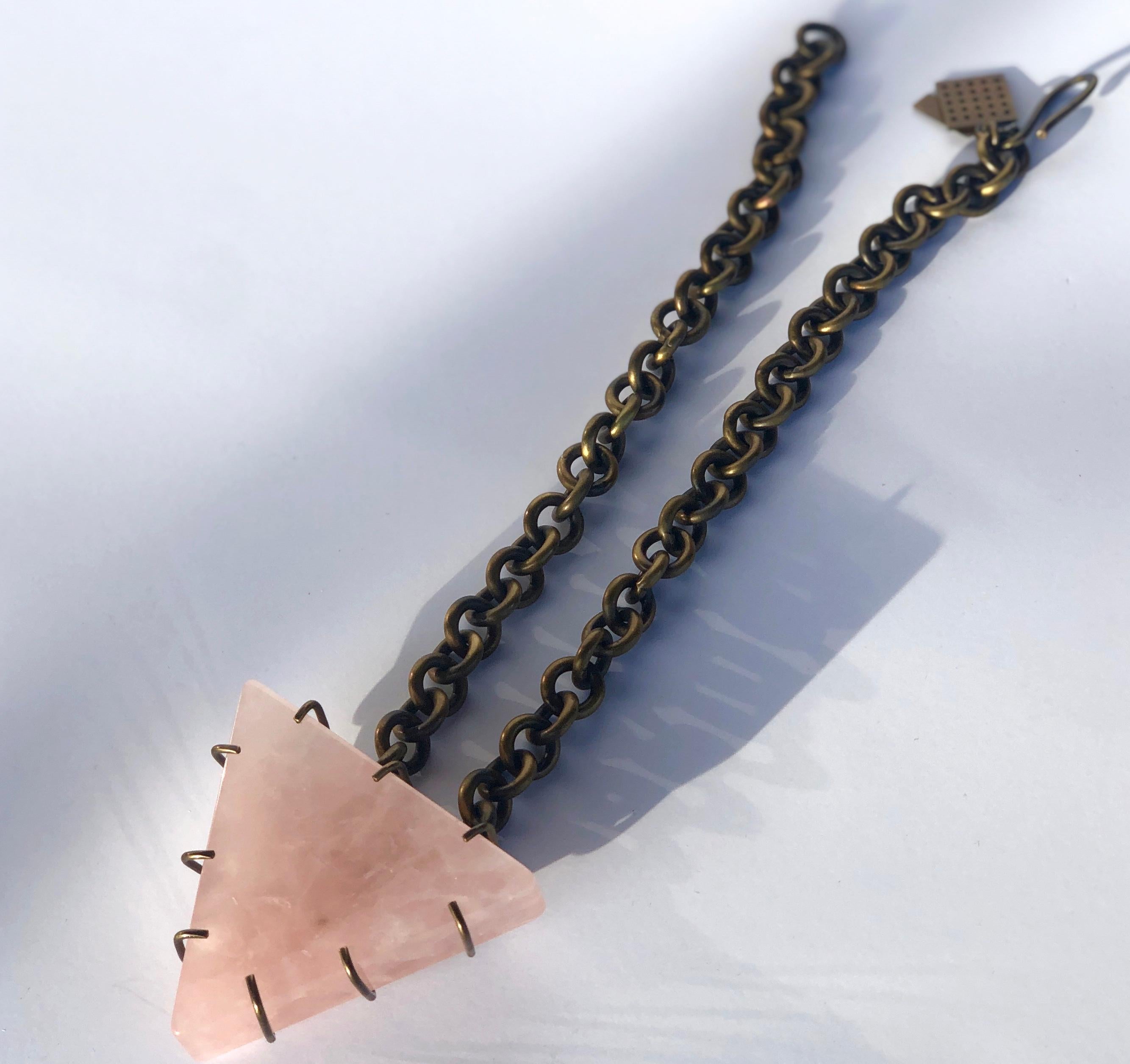 Offered is a signed Kelly Wearstler triangular large pink quartz pendent held by bronze prongs and bronze chain link necklace.
Make:  Kelly Wearstler
Place of manufacture:  United States
Color:  Pink and bronze
Materials:  Pink quartz and