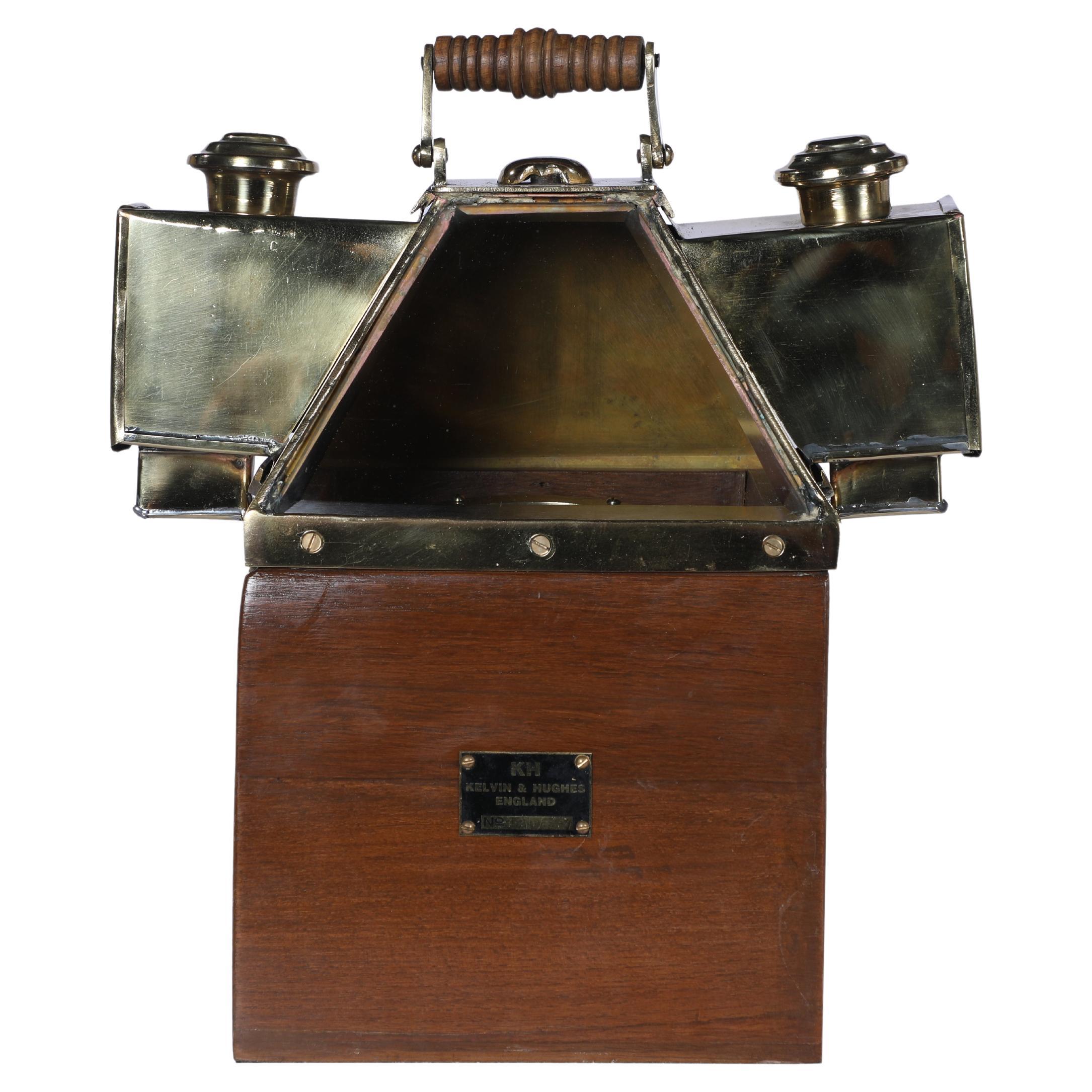 A documented Kelvin and Hughes brass binnacle compass in working order. It sits in a teak case with brass oil lights on either side. The small doors on each side open and the oil lamps slide out for lighting. Maker's plaque on the front indicating a