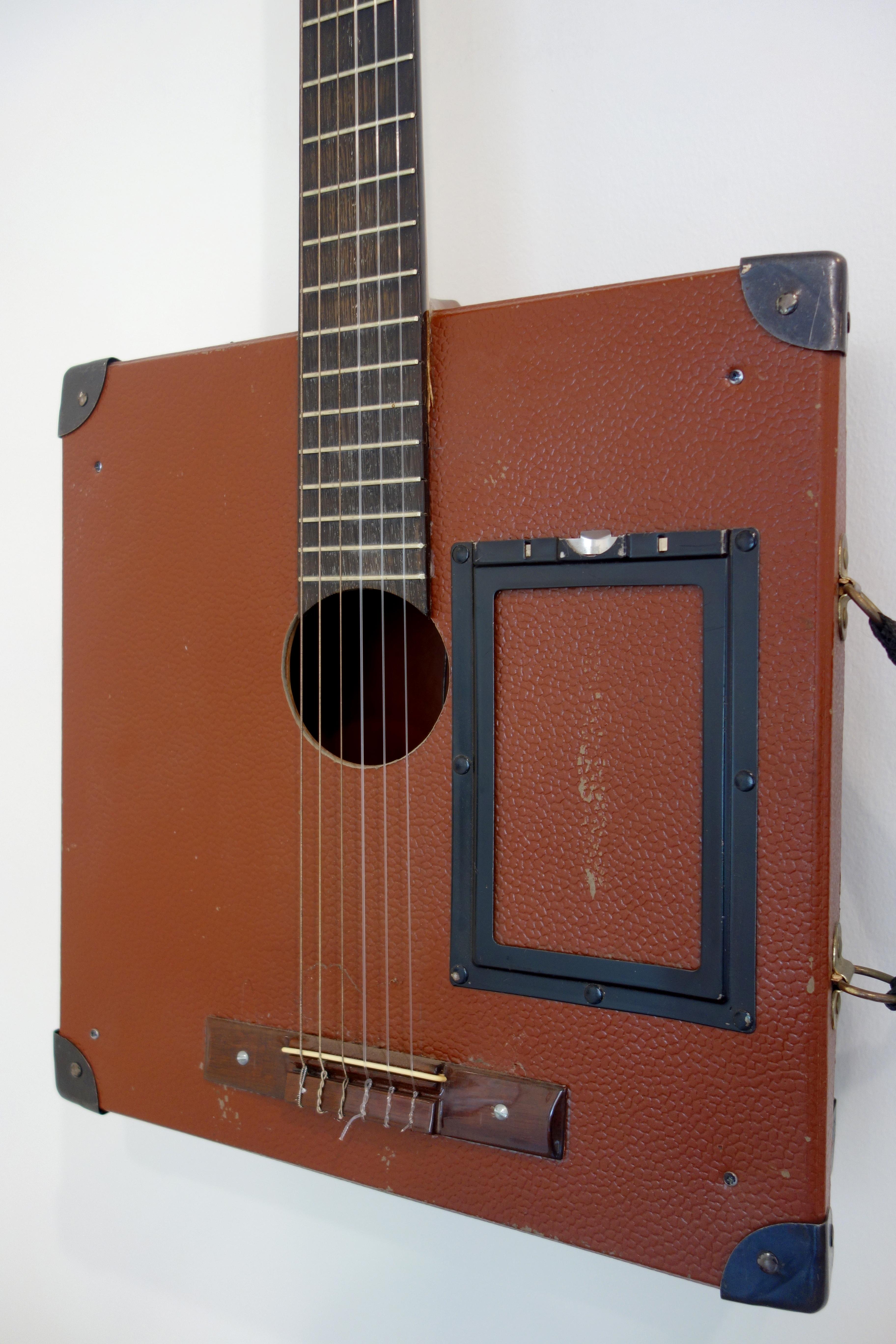 Questa scultura di chitarra acustica creata da Ken Butler è in parte chitarra e in parte custodia di una bobina cinematografica vintage. È realizzato nello spirito dell'assurdità che molti surrealisti hanno abbracciato utilizzando oggetti trovati in
