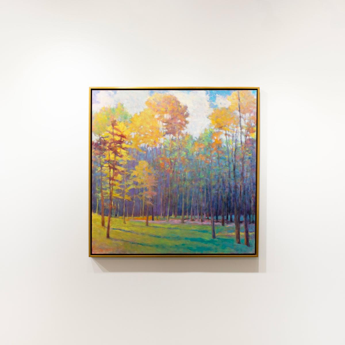 This framed abstracted landscape painting by Ken Elliott features forest landscape composition and a colorful palette with contrasting warm and cool tones. Large trees cast cool blue shadows over a grassy forest floor. The painting is made with oil