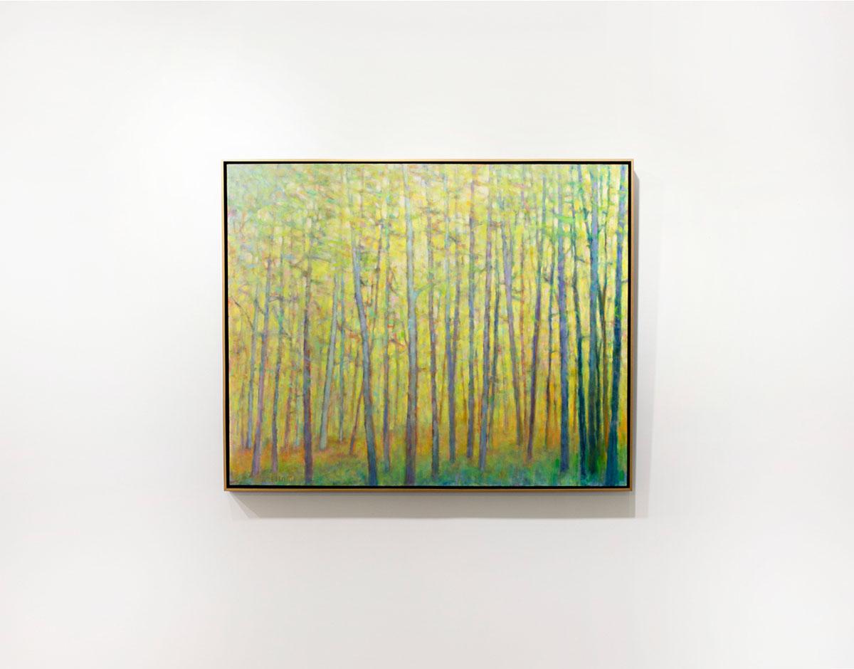 This framed abstracted landscape painting by Ken Elliott features forest landscape composition and a colorful yellow and green palette. Cool-toned tree trunks are contrasted by warm yellow and green tones between them. The painting is made with oil