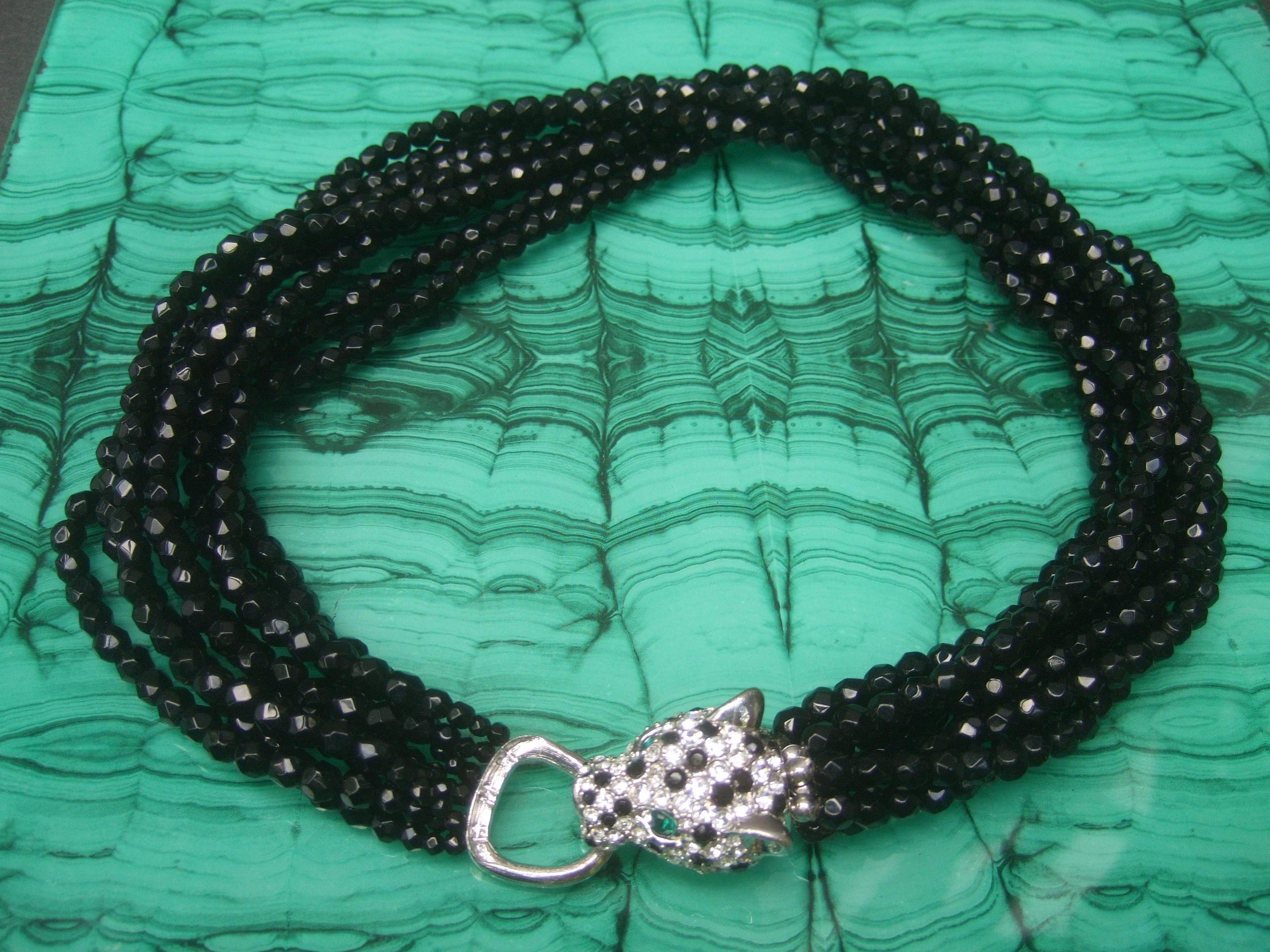 Ken Lane Exquisite jet glass beaded jeweled panther clasp choker style necklace c 1980
The elegant glass beaded necklace is designed with eight strands of black faceted glass beads
The clasp is adorned with an exquisite crystal encrusted panther's