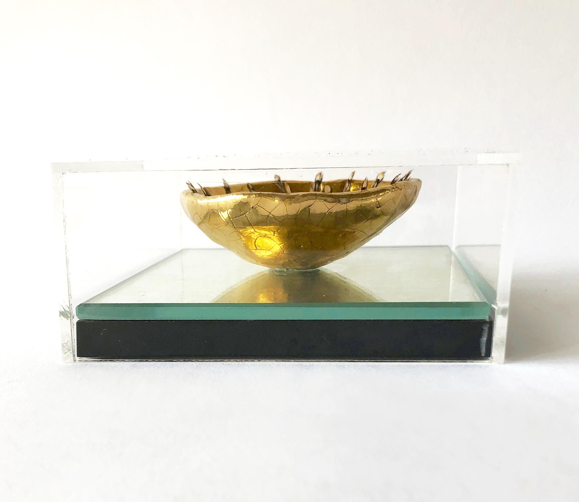 Gold luster funk pottery fetish bowl embellished with applied feathers at its rim created by Ken Shores of Oregon, circa 1960s. Bowl is mounted in an acrylic plexiglass box with mirrored backing measuring 5 1/4